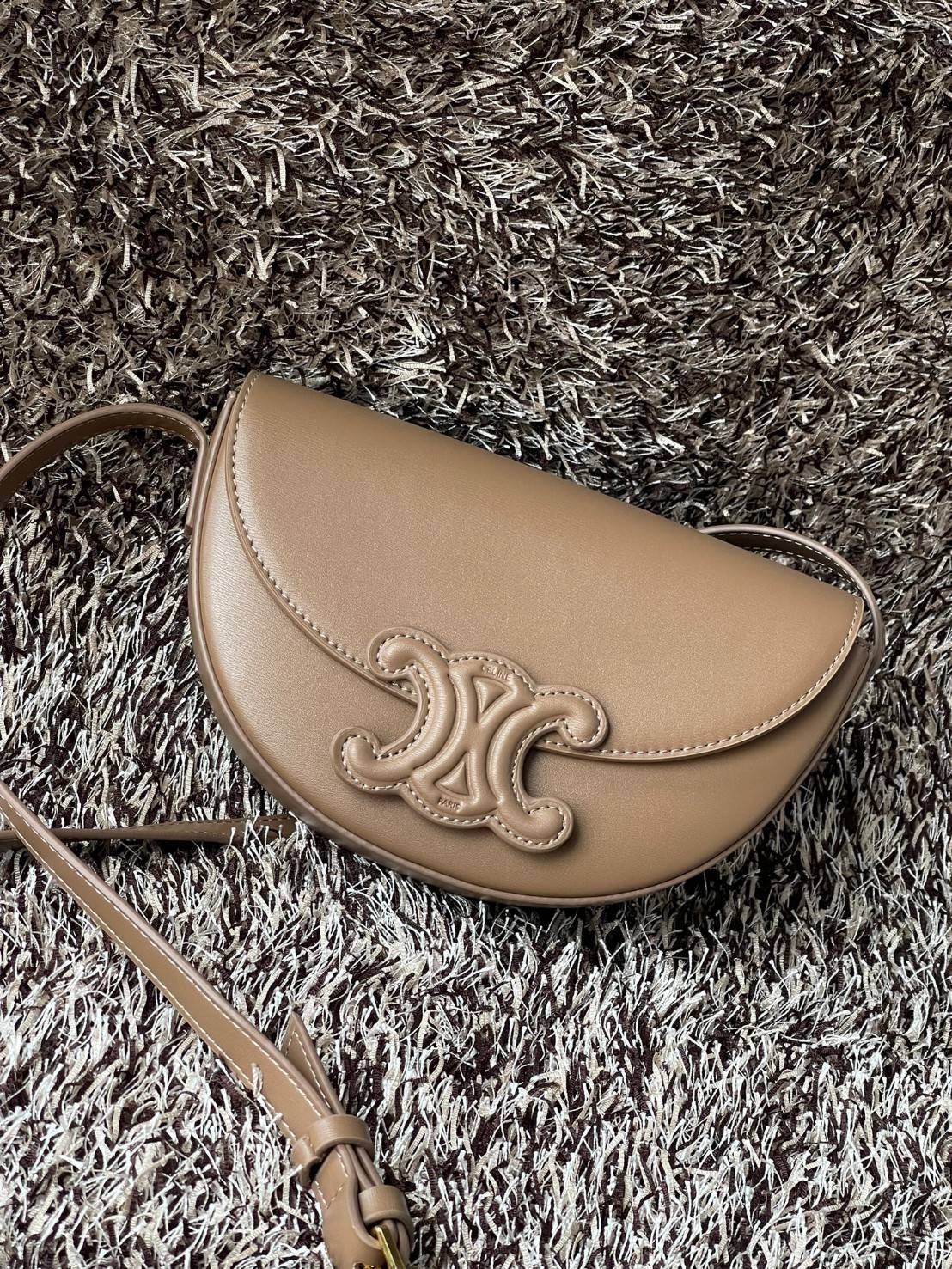 CELINE BESACE CUIR TRIOMPHE IN SMOOTH กระเป๋ารุ่นนี้นำเสนอในรูปทรงฮาล์ฟมูนที่ตอนนี้กำลังงมาแรง เปิดด้วยกระดุมแป๊กเพื่อเผยให้เห็นช่องภายในที่กว้างขวางและกระเป๋าด้านในแบบแบน คุณสมบัติที่โดดเด่นอีกอย่างของกระเป๋าอยู่ที่โลโก้ขนาดใหญ่ รูปทรงสะดุดตา สามารถสะพาย