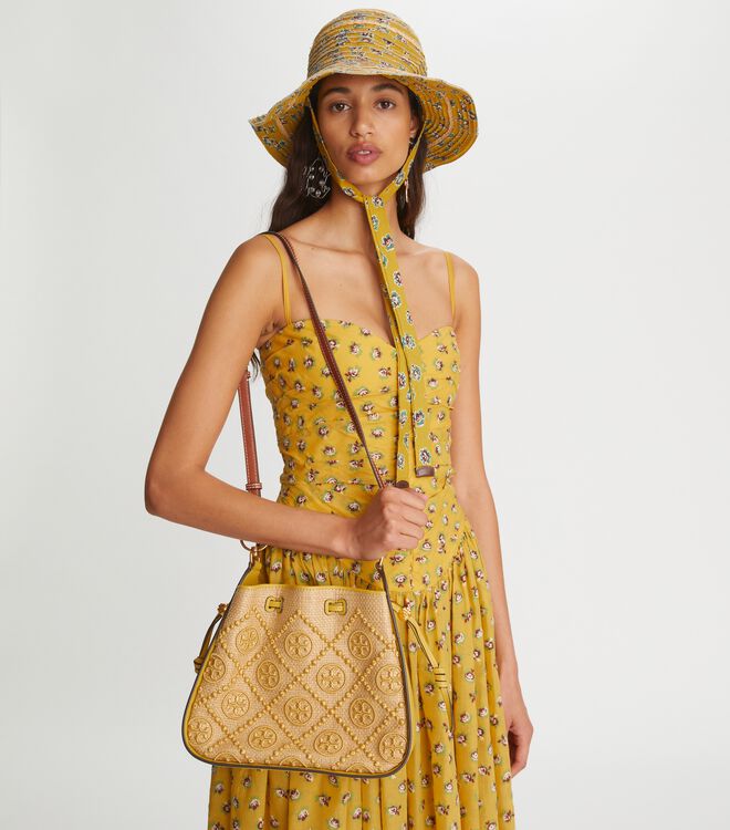 TORY BURCH T Monogram Straw Bell Bag กระเป๋าสะพายข้างรุ่นคลาสสิกที่ได้แรงบันดาลใจจากการควิลท์แบบดั้งเดิมของเพนซิลเวเนีย คอลเลกชันบ่งบอกถึงความมีสไตล์เหนือกาลเวลา รูปทรงเรียวโดดเด่น ปักทอลายแบรนด์อย่างสวยงาม เปิด ปิดด้วยเชือกรูด ด้านในช่องโล่งกว้าง ซับในผ้