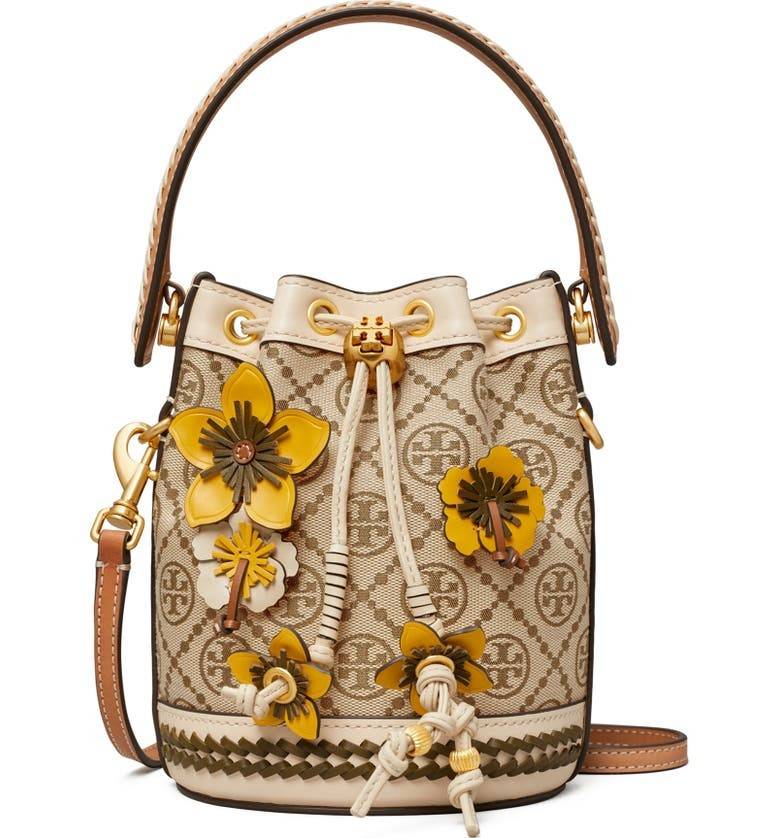 TORY BURCH MINI T MONOGRAM FLORAL BUCKET BAG คอลเลคชั่นใหม่ พร้อมเสิร์ฟความสวยให้ถึงบ้าน!! กระเป๋าบัคเก็ตทรงยอดนิยม ไซส์มินิ ดีไซน์ใหม่ล่าสุด สไตล์งานคราฟ มีลูกเล่นประดับดอกไม้กับตัวกระเป๋า และตัวรูดสาย วัสดุผ้า jacquard ตัดสลับหนังแท้ หูจับและขอบกระเป๋าต