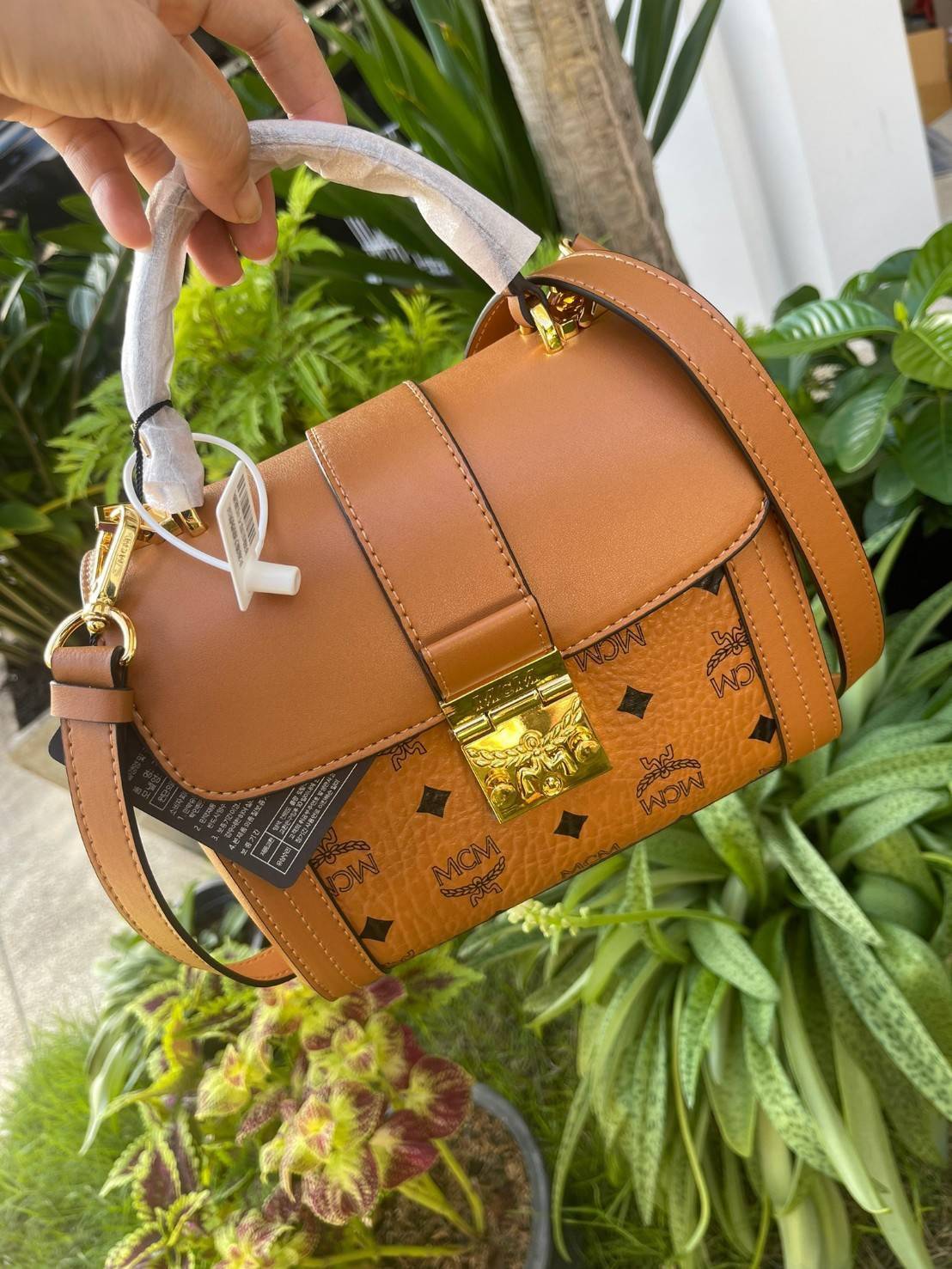 M.C.M Tracy Satchel in Visetos กระเป๋าทรงนักเรียน Tracy ขนาดเล็กผสานความประณีตที่อ่อนนุ่มของหนังดิบ (Vachetta) เข้ากับสัญลักษณ์อันเป็นมรดกของผ้าใบเคลือบผิวลาย Visetos ปิดด้วยตัวล็อคลอเรลนับเป็นความหรูหราที่มาพร้อมพื้นที่เก็บของจำเป็นอย่างกว้างขวาง