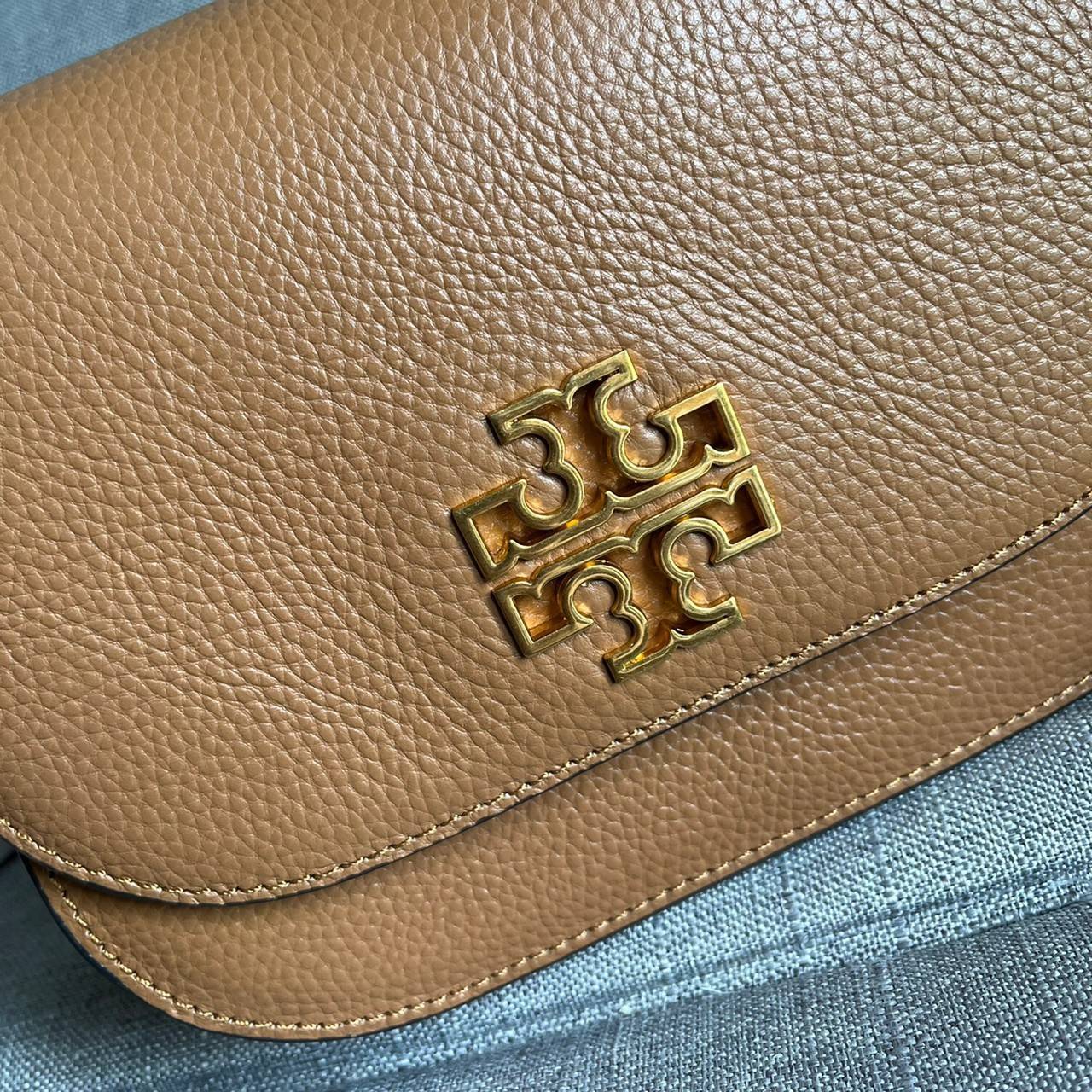 TORY BURCH BRLTTEN SMALL SADDLE BAG / Tory Burch Britten Flap Shoulder Bag กระเป๋าสะพายข้าง วัสดุหนังแกะแท้ ด้านหน้าประดับโลโก้แบรนด์ เปิด-ปิดกระเป๋าแบบกระดุมแป็กแม่เหล็กแน่นหนา ภายในมีช่องหลัก ใส่กระเป๋าเงินใบกลาง มือถือได้ทุกรุ่น มีช่องแยกใส่ของจุกจิกอี