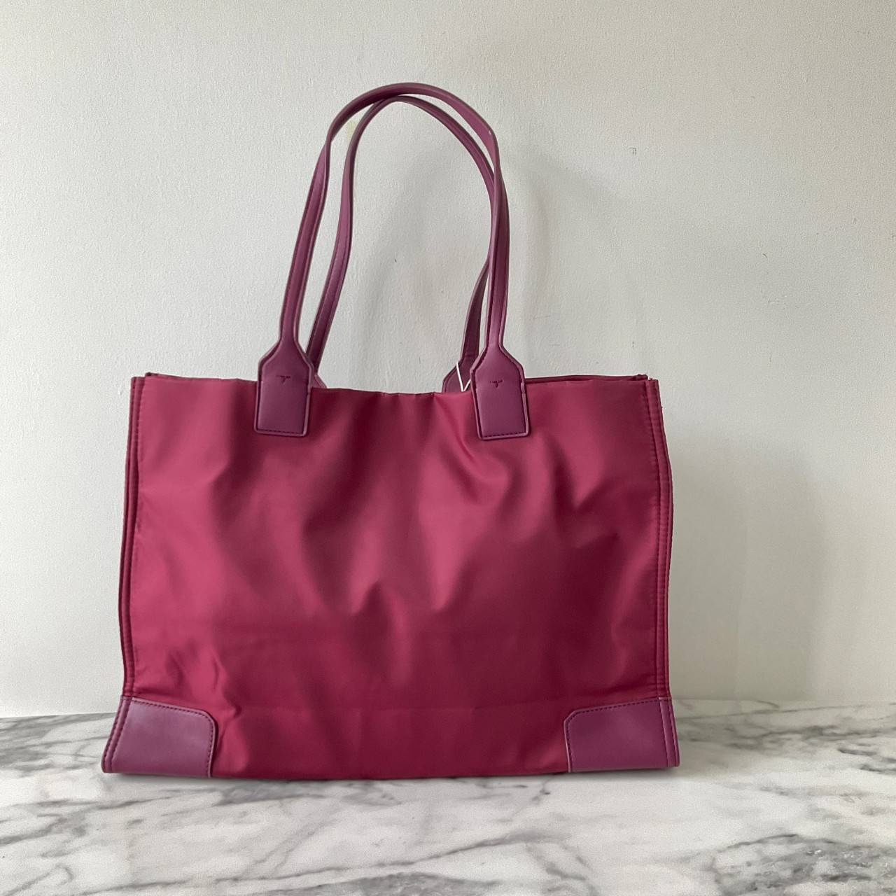 กระเป๋าทรงโท้ทใบใหญ่ TORY BURCH ELLA TOTE BAG วัสดุ NYLON ทั้งใบตัดด้วยหนังสีดำ แต่งโลโก้แบรนด์ด้านหน้า ด้านข้างมีกระดุม สามารถขยายทรงได้ ด้านในเปิดปิดด้วยกระดุมแม่เหล็กฝัง ช่องกว้างหลักหนึ่งช่องและช่องซิปอีกช่อง สามารถใส่แล็ปท็อปได้สบาย ใบใหญ่เว่อวัง ไอเ