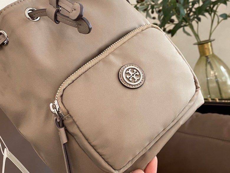 Tory Burch Virginia Nylon Bucket Bag / Tory Burch logo-plaque bucket bag กระเป๋าสะพายทรงบัคเก็ต เปิด-ปิดหนังรูดปากกระเป๋า มีหูหิ้วในตัว คล้องแขนเก๋ๆ ภายในเป็นช่องโล่ง มีช่องย่อย ใส่ของสำคัญจุกจิกได้ มีสายครอส จะสะพายไปไหนก็ได้ทุกโอกาส สวยเลิศทุกสี พร้อมส่
