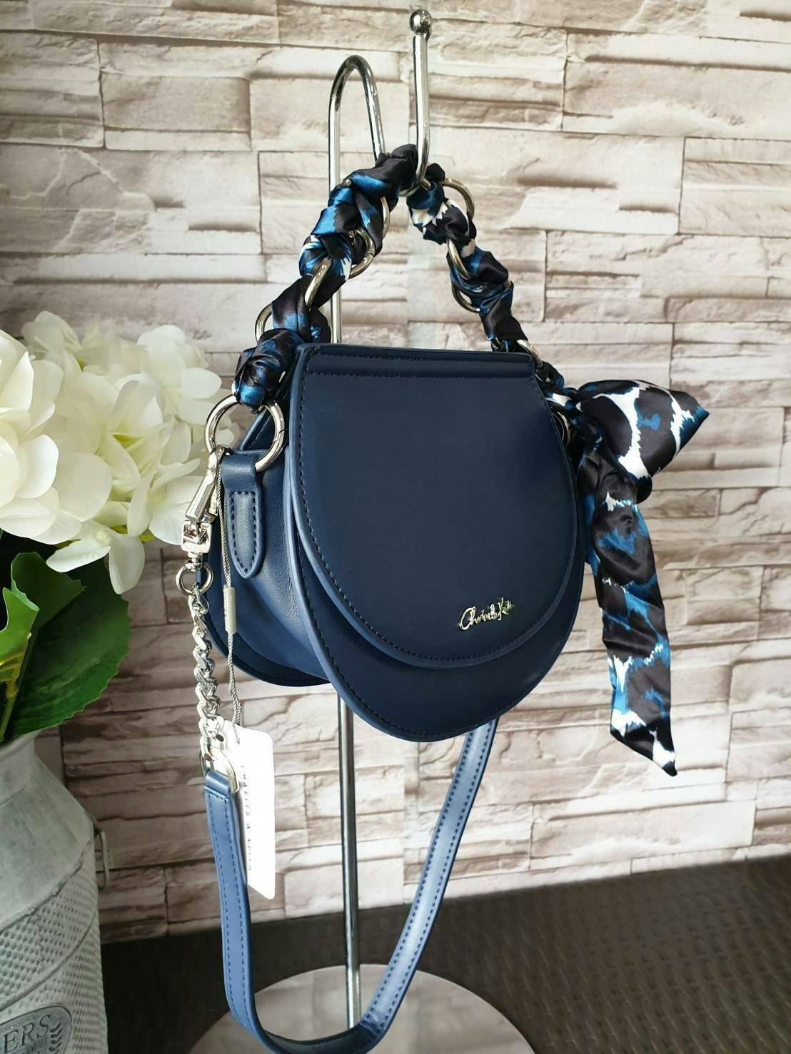 CHARLES & KEITH รุ่น LEATHER SATIN SCARF CROSSBODY BAG SL2-50150828 ราคาปกติช้อป ( ฿3,590.00 ) กระเป๋าถือ และ สะพาย ทรงโค้งมน หนังเรียบ ตั้งอยู่ทรง ด้านหน้าติดโลโก้แบรนด์ อะไหล่เงิน หูจับสายกระเป๋าร้อยเข้ากับห่วงเหล็กกลมๆ ด้วยผ้าลายสวยงามผูกเป็นโบว์เก๋ๆ ถ