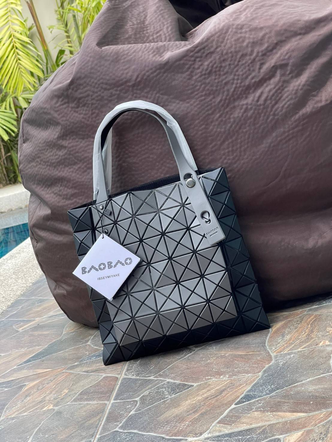 Baobao Issey Miyake Prism Kangaroo tote bag กระเป๋าถือทรงโท้ทที่ประดิษฐ์ขึ้นอย่างเชี่ยวชาญในญี่ปุ่น มาพร้อมแผงเรขาคณิตสำหรับการออกแบบที่ได้รับแรงบันดาลใจจากกระดาษพับ ซิลลูเอทอันเป็นเอกลักษณ์นี้ปิดท้ายด้วยสายรัดแบบอสมมาตร มีการพัฒนาโครงสร้างทรงสามเหลี่ยมเพ