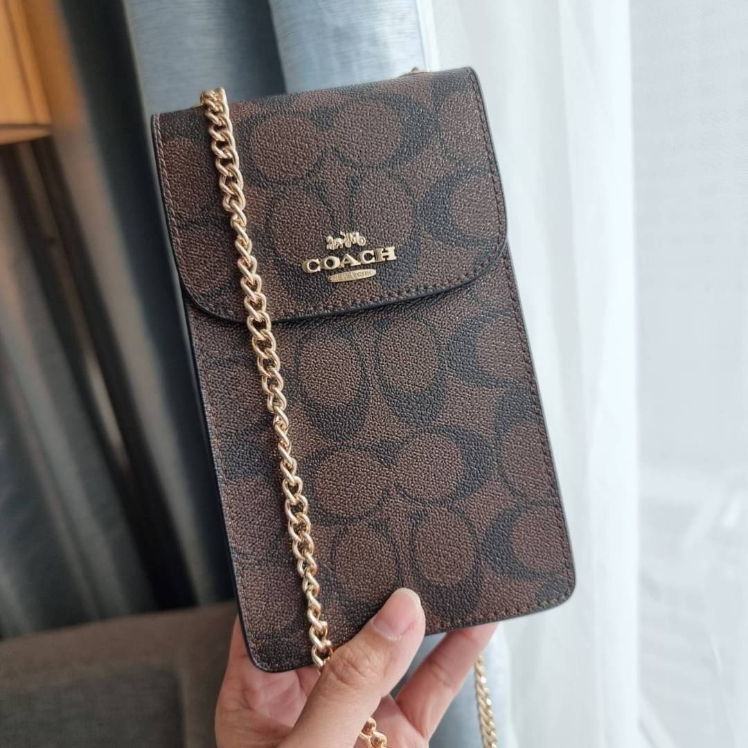 COACH NORTH/SOUTH PHONE CROSSBODY IN SIGNATURE CANVAS F55636 F39955 สุดคลาสสิคกับกระเป๋าสะพายเอนกประสงค์ Case phone ใส่โทรศัพท์มือถือได้ทุกรุ่น ดีไซน์ลายเอกลักษณ์ วัสดุหนังแคนวาสเคลือบลาย ฝาและภายในเป็นหนังสังเคราะห์เรียบ เปิด-ปิดด้วยกระดุม สายสะพายยาวประ