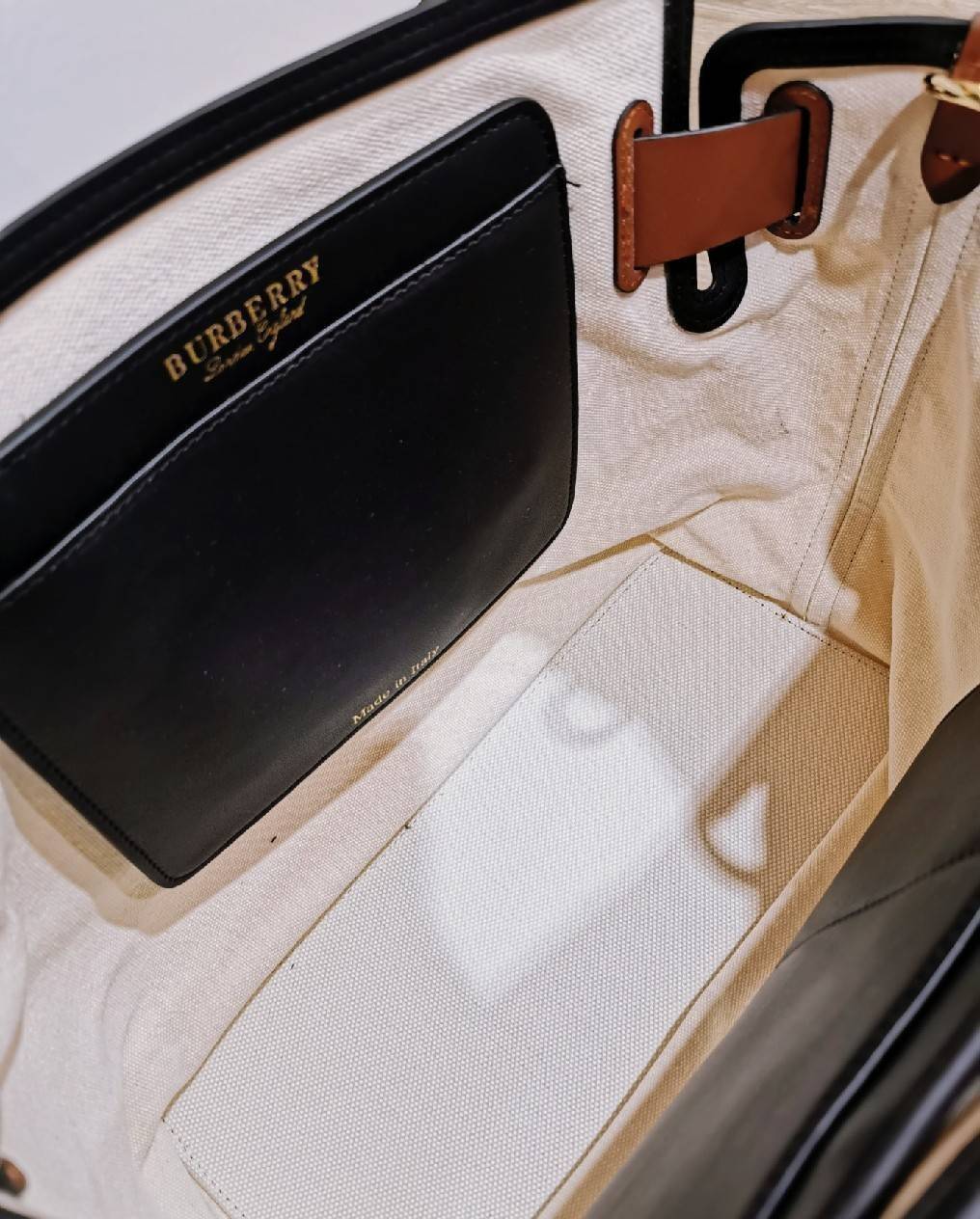 BURBERRY FRAGRANCES TOTE BAG อีกหนึ่งไอเท็มหายาก วัสดุ Canvas & Leather Calfskin ดีไซน์สวยมีเอกลักษณ์คาดด้วยสายหนังประดับกระดุมทองด้านหน้า หูจับหนังแท้จับถนัดมือ สายสะพายยาวหนังแท้ถอดได้ปรับระดับได้อะไหล่แบรนด์ ภายในโล่งกว้างมีช่องใส่ของใส่เอกสารA4 กระเป๋