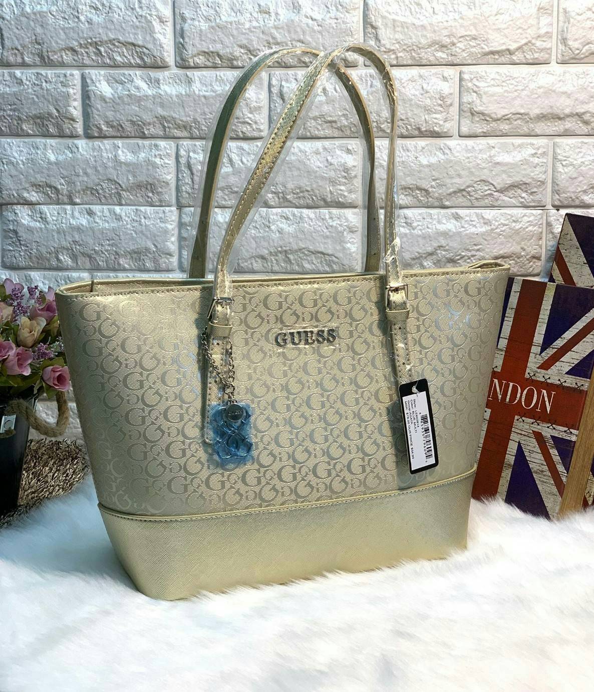 GUESS WOMEN LARGE TOTE BAG กระเป๋าถือ//สะพายไหล่ ทรง Tote ตัวกระเป๋าลายแบรนด์ทั้งใบ ผสมหนังซาฟเฟียโน่ตรงขอบล่างกระเป๋าค่ะ ด้านหน้าห้อยอะไหล่แบรนด์มาให้ เปิดปิดกระเป๋าแบบซิป ภายในโล่ง กว้าง ใส่ของได้จุค่ะ มีช่องซิปและช่องเล็กใส่ของจุกจิกนะค่ะ หูหิ้วสามารถป