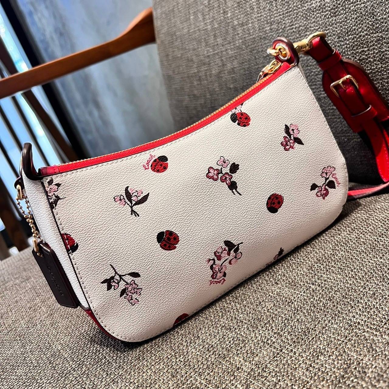 COACH C7973 JES BAGUETTE WITH LADYBUG FLORAL PRINT คอลเลคชั่นใหม่ล่าสุด พร้อมเสิร์ฟความสวยถึงบ้านเช่นเคย!! กระเป๋าสะพายทรงบาแกตต์ ดีไซน์ย้อนยุค ที่แอบแฝงความเรียบหรูดูแพงอยู่ในตัว โดดเด่นด้วยสายสะพายเส้นใหญ่ โทนสีคอนทราส ทำให้ไอเท็มนี้ดูมีลูกเล่นมากขึ้น ว