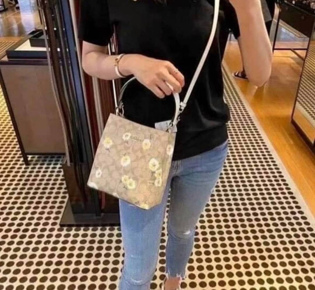 OUTLET 】COACH C3411 SMALL TOWN BUCKET BAG IN SIGNATURE CANVAS WITH DAISY PRINT สวยสดใสมาให้ถึงบ้านจ้า!! กระเป๋าทรงบัคเก็ตยอดฮิต รอบนี้น่ารักมุ้งมิ้งไม่เลิก ดีไซน์ลายดอกเดซี่คละรอบใบ วัสดุหนังแคนวาสเคลือบลาย ปากกระเป๋าเปิด-ปิดด้วยกระดุมแม่เหล็ก 2ฝั่ง มีหูจ
