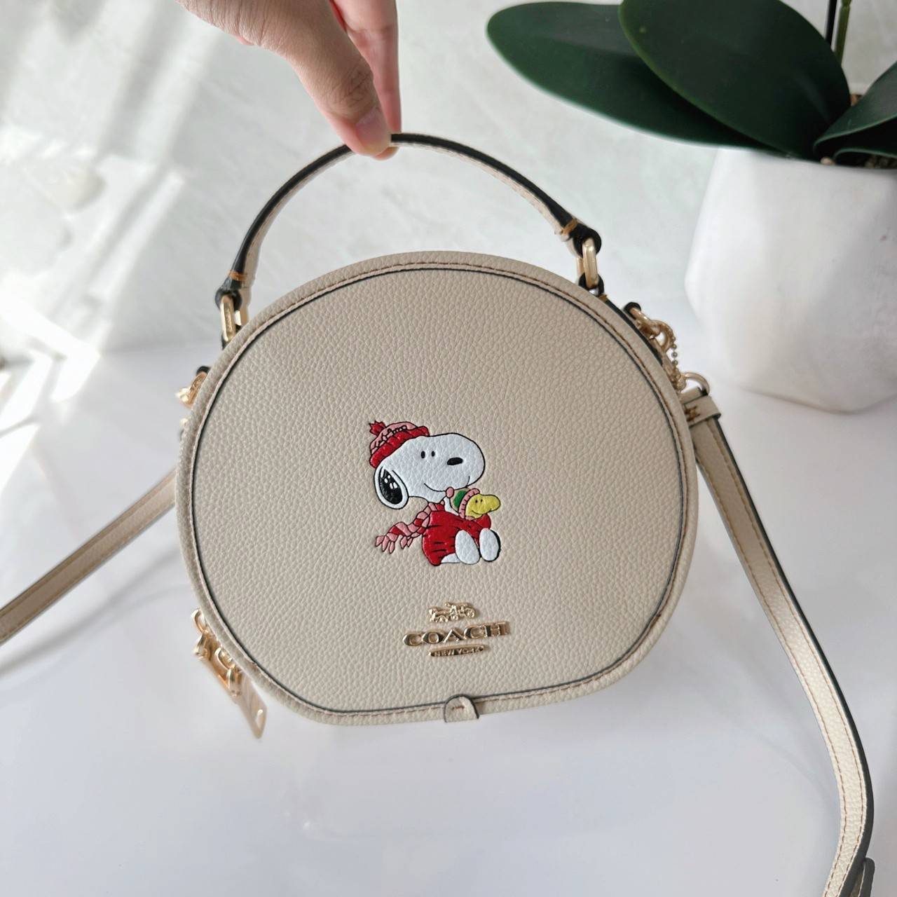 COACH X PEANUTS CANTEEN CROSSBODY WITH SNOOPY PRESENT MOTIF (CE845,CF290) กระเป๋าสะพายข้างทรงกลมไซส์มินิ มีหูจับ วัสหนังแท้ ด้านหน้าโดดเด่นด้วยรูปการ์ตูนSnoopy