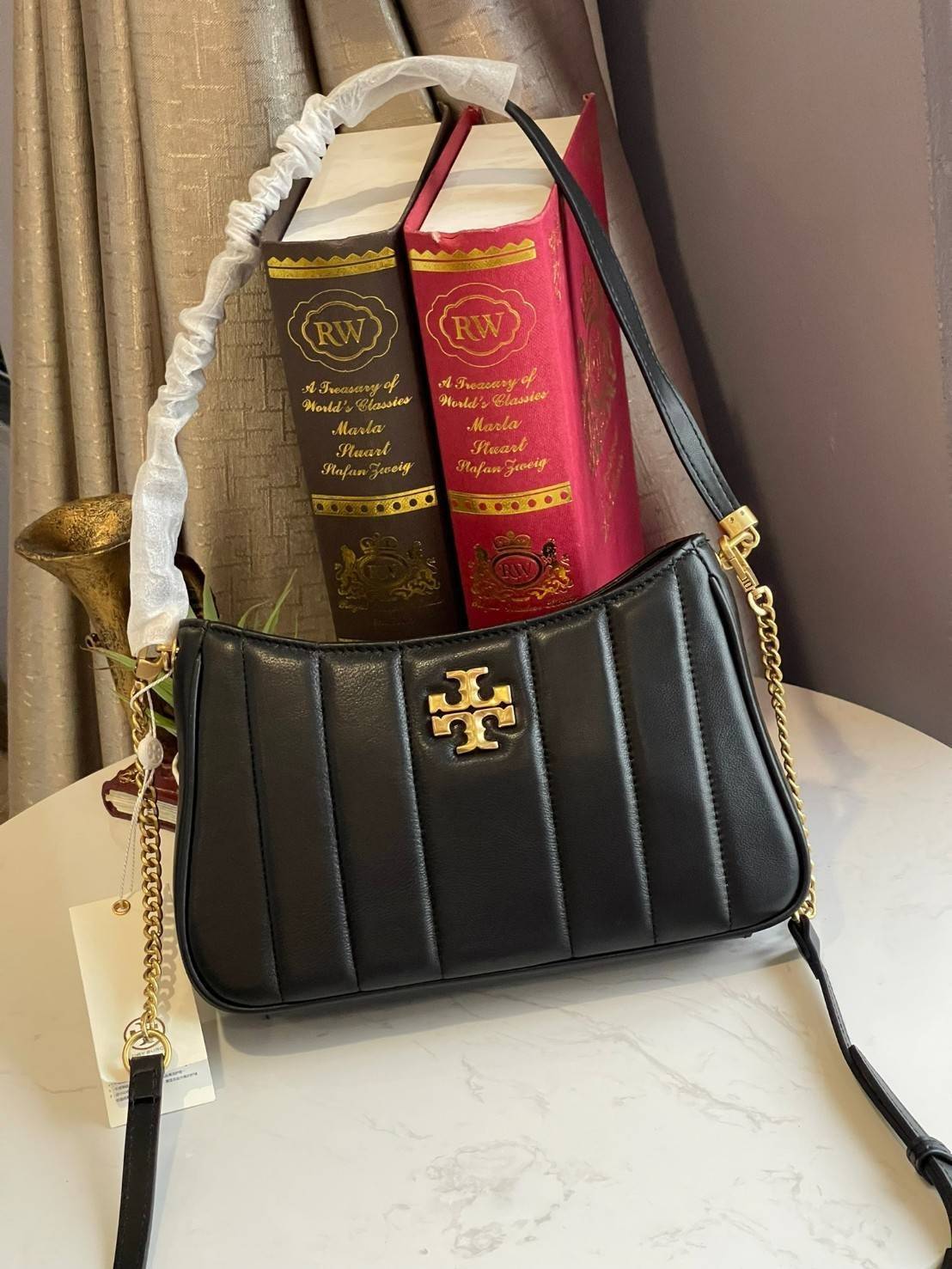 Tory burch Kira logo-plaque crossbody bag กระเป๋า Kira ของ Tory Burch เป็นส่วนหนึ่งของคอลเล็กชั่นที่โดดเด่น และมีหลายรุ่นด้วยกัน โดยมีป้ายโลโก้ Double T ของแบรนด์อยู่ตรงกลาง มีความเรียบง่ายแต่ยังคงความหรูหราโดดเด่นด้วยวัสดุบุผิว ป้ายโลโก้สีทอง สายสะพายโซ่