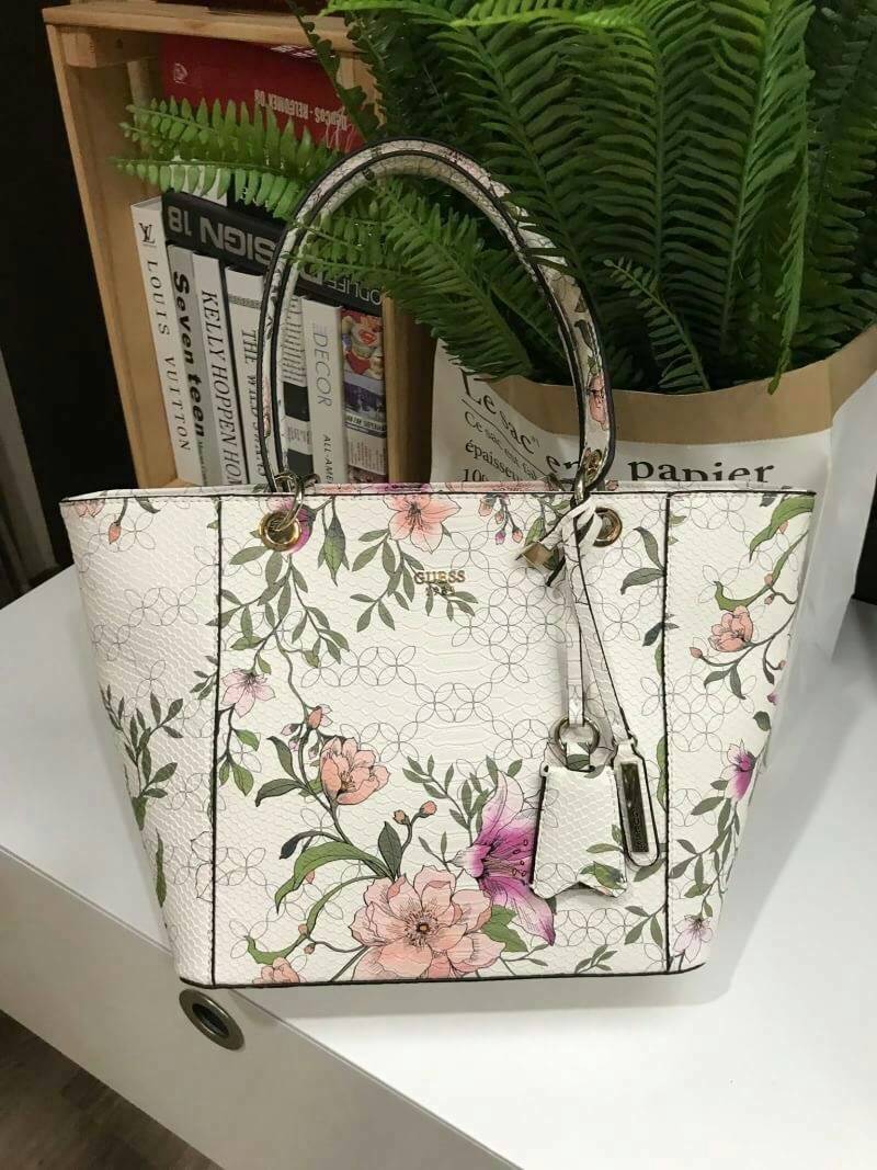 GUESS PRINTED KAMRYN FLOWERS SHOPPER BAG (SIZE L) กระเป๋าสะพายจาก GUESS FACTORY หนังสวยอยู่ทรงปริ้นลายดอกไม้คอลเลคชั่นล่าสุดใบใหญ่กำลังดี ใส่สัมภาระได้จุใจ น้ำหนักเบา ด้านหน้าประดับโลโก้แบรนด์อะไหล่เงินพร้อมพวงกุญแจแบรนด์ห้อยที่หูหิ้วถอดเเยกใช้ได้ หูหิ้วพ