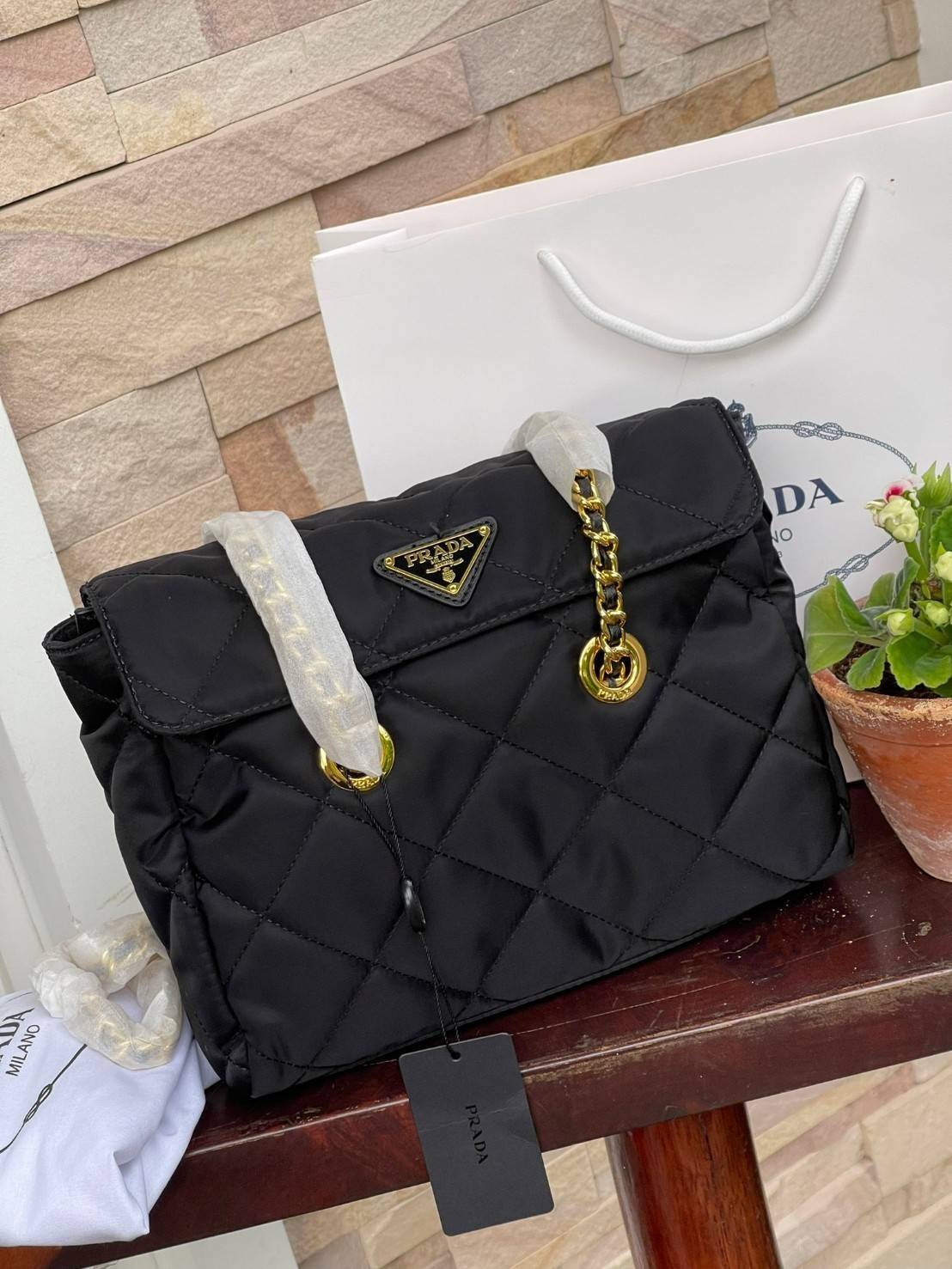 Prada Black Quilted Nylon Vintage Shoulder Bag ถือว่าเป็นแบรนด์ที่ได้รับการขนานนามว่าเป็น "แบรนด์คลาสสิกที่แปลกใหม่ ดูเก่าแต่ทันสมัย" กระเป๋าสะพายไหล่ใบนี้ วัสดุเป็นไนลอนที่ถือเป็น Iconic ของแบรนด์ มาพร้อมกับดีเทลที่ใช้สายสะพายโซ่ร้อยเข้ากับหนัง