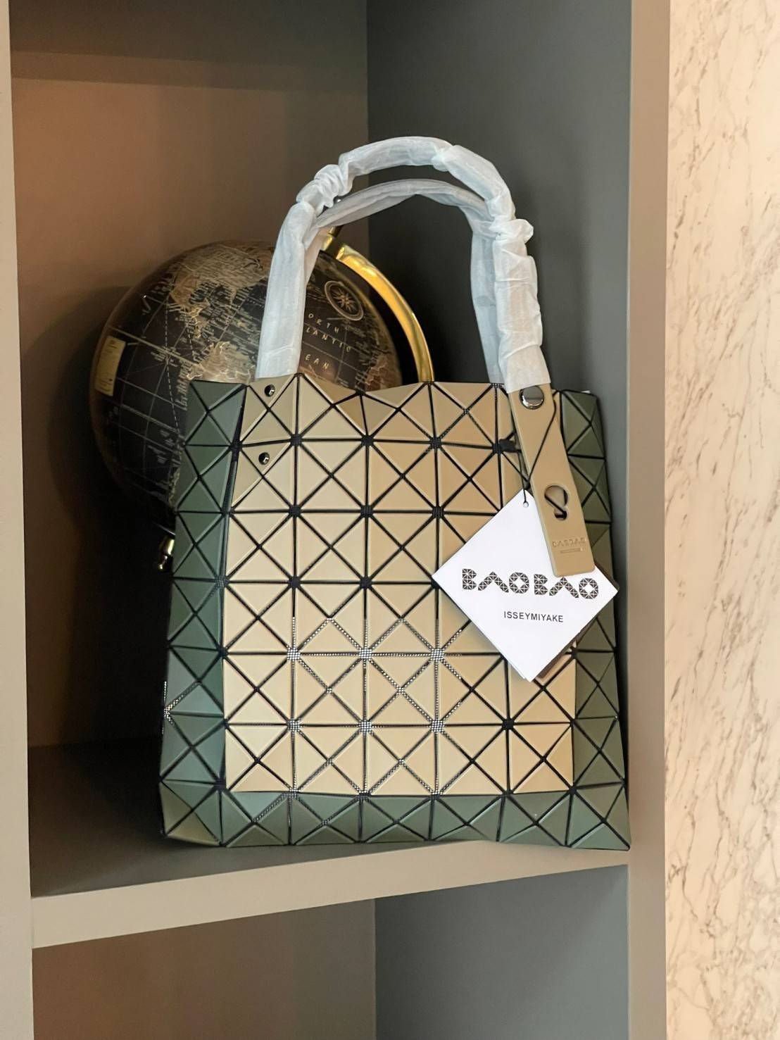 Baobao Issey Miyake Prism Kangaroo tote bag กระเป๋าถือทรงโท้ทที่ประดิษฐ์ขึ้นอย่างเชี่ยวชาญในญี่ปุ่น มาพร้อมแผงเรขาคณิตสำหรับการออกแบบที่ได้รับแรงบันดาลใจจากกระดาษพับ ซิลลูเอทอันเป็นเอกลักษณ์นี้ปิดท้ายด้วยสายรัดแบบอสมมาตร มีการพัฒนาโครงสร้างทรงสามเหลี่ยมเพ