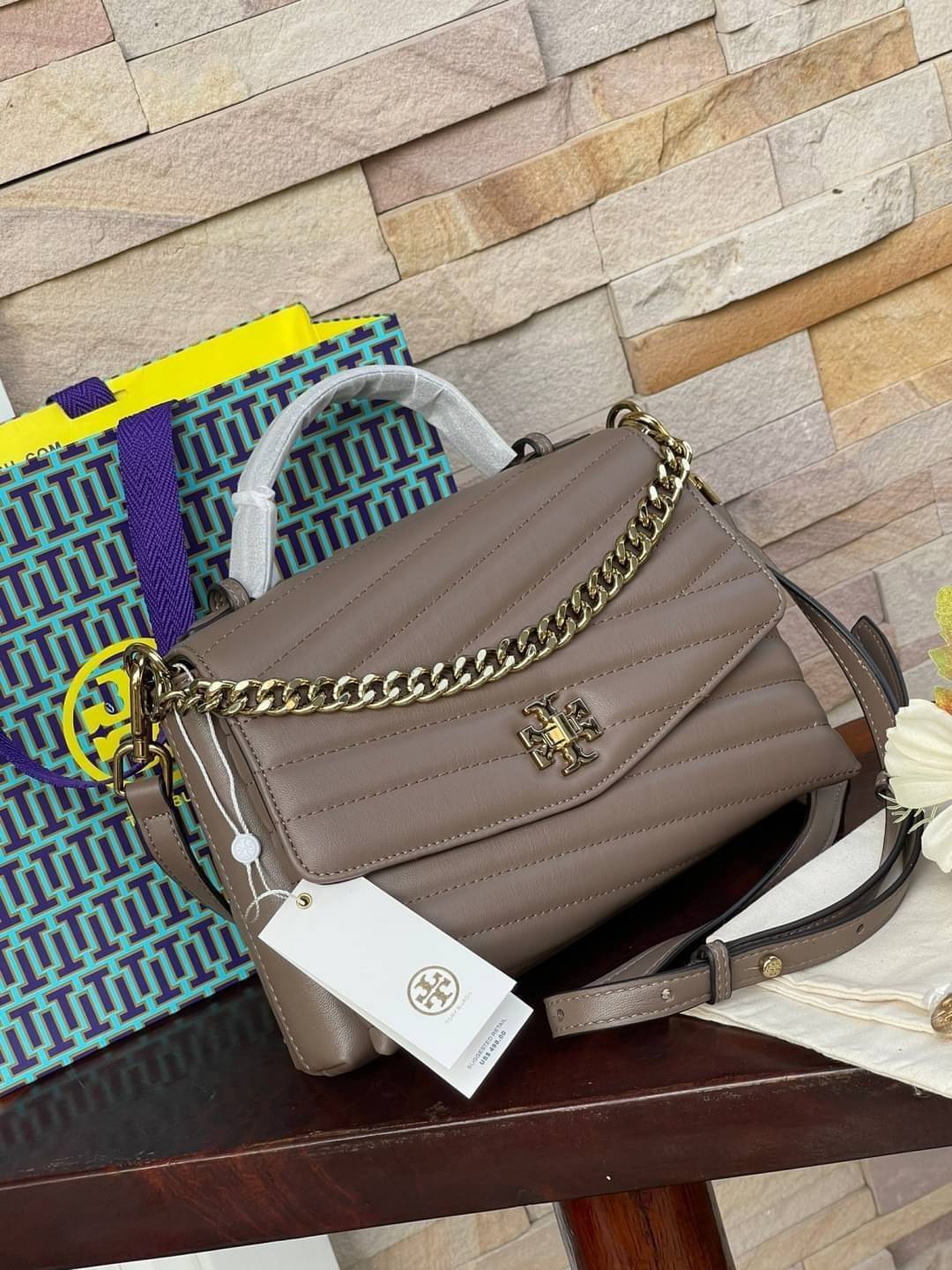 TORY BURCH Kira Chevron Top-handle Satchel กระเป๋าหนังแกะ สัมผัสนุ่มควบคู่กับดีไซน์อันเป็นเอกลักษณ์ กระเป๋าถือทรงสวยที่มีดีไซน์อันเป็นเอกลักษณ์ไม่เหมือนกับที่ไหน ด้วยการตัดเย็บหนังแกะแสนนุ่มแบบลายบุสองชั้น เพิ่มมูลค่าด้วยสายสะพายที่ทำจากโลหะสีทอง อีกทั้งย