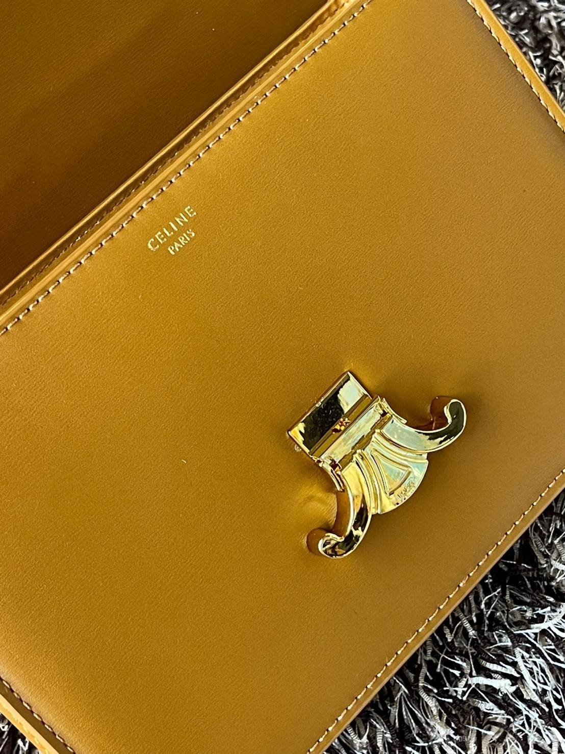 Celine MEDIUM TRIOMPHE BAG IN SHINY มีรูปทรงเป็นกล่องคล้ายกับกระเป๋า Classic Box แต่มีการออกแบบโลโก้ที่สะดุดตาแบบวินเทจ ด้วยดีไซน์ที่ดูโฉบเฉี่ยว แต่คงความคลาสสิคอย่างเต็มเปี่ยม ทำให้เป็นที่ดึงดูดความสนใจของสาวๆ สายสะพายสามารถปรับระดับได้ มีความคล่องตัวในก