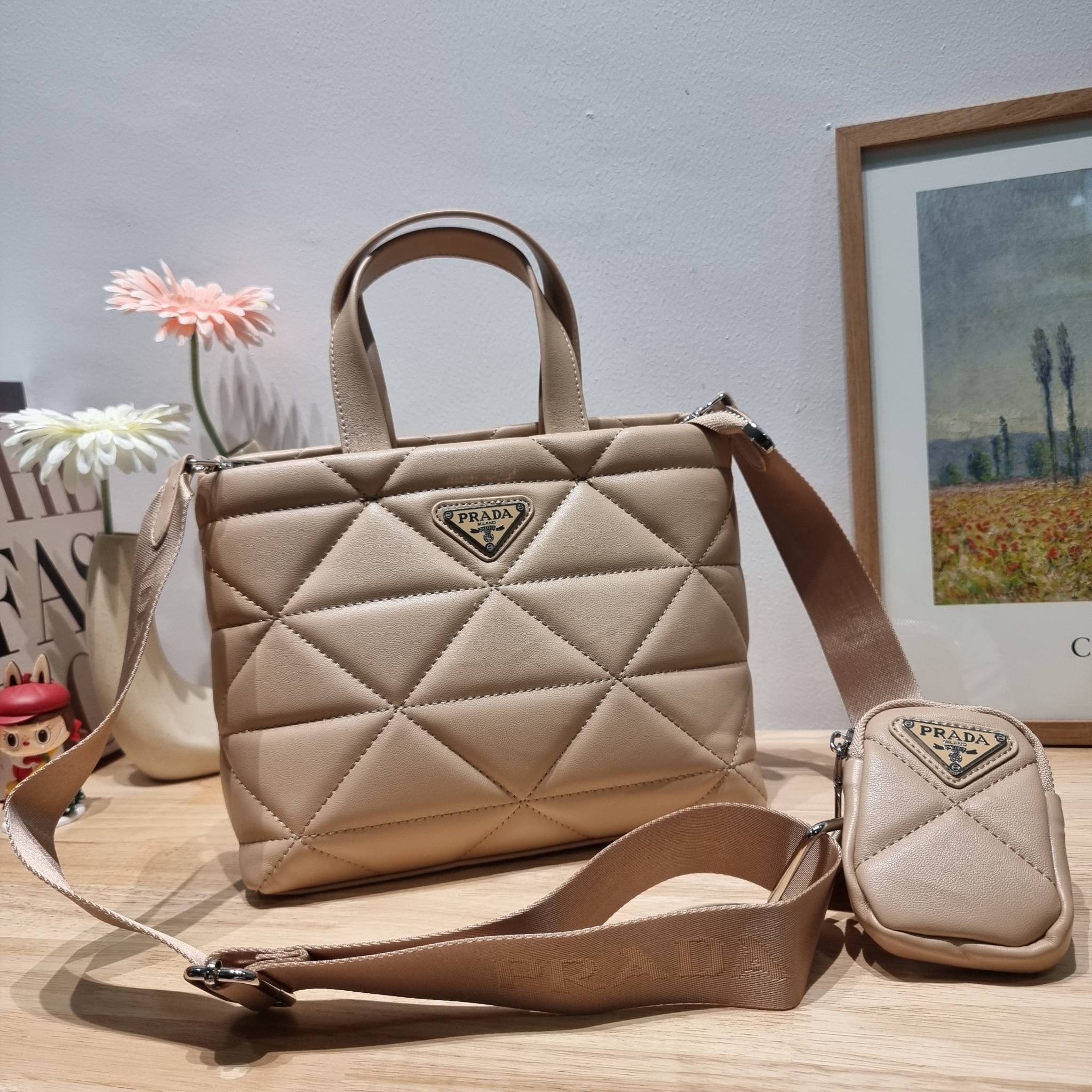 PRADA LEATHER PADDED BAG ใหม่ล่าสุด กับคอลเลคชั่นที่ทำออกมาตอบโจทย์ได้ทุกไลฟ์สไตล์ และเป็นยูนิเซ็กส์ กับกระเป๋าทรงโท้ท ขนาดกำลังดี วัสดุหนังเรียบ ตัดเย็บเดินเส้นลายตาราง ปากกระเป๋ามีซิปเปิดปิด ภายในเป็นช่องโล่ง