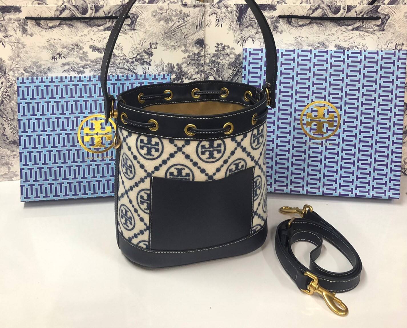 Medium : Tory Burch T Monogram Chenille Bucket Bag เปิดตัวอีกหนึ่งรุ่นกับกระเป๋าลาย T MONOGRAM รุ่นใหม่ล่าสุดจาก TORY BURCH พลาดไม่ได้กับโลโก้สุดคลาสสิก ลวดลาย T Monogram คือวัสดุ chenille หรือที่เรียกว่า ด้านไหมกำมะหยี่ มารังสรรค์ลงบนกระเป๋าBucketใบนี้ เ