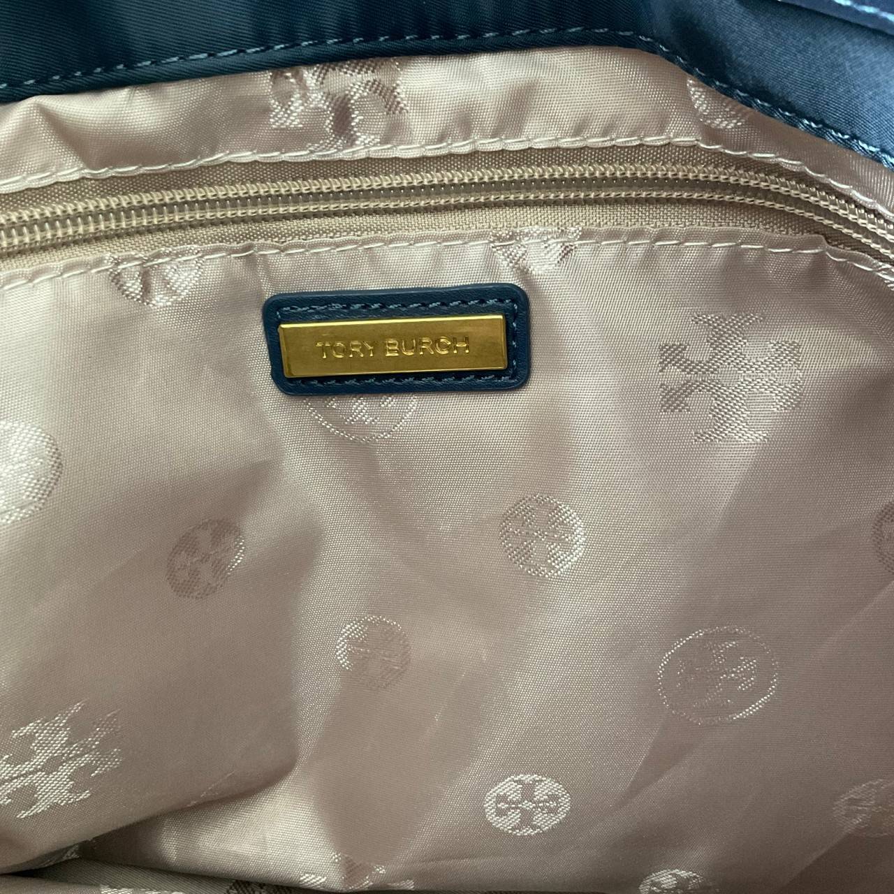 กระเป๋าทรงโท้ทใบใหญ่ TORY BURCH ELLA TOTE BAG วัสดุ NYLON ทั้งใบตัดด้วยหนังสีดำ แต่งโลโก้แบรนด์ด้านหน้า ด้านข้างมีกระดุม สามารถขยายทรงได้ ด้านในเปิดปิดด้วยกระดุมแม่เหล็กฝัง ช่องกว้างหลักหนึ่งช่องและช่องซิปอีกช่อง สามารถใส่แล็ปท็อปได้สบาย ใบใหญ่เว่อวัง ไอเ