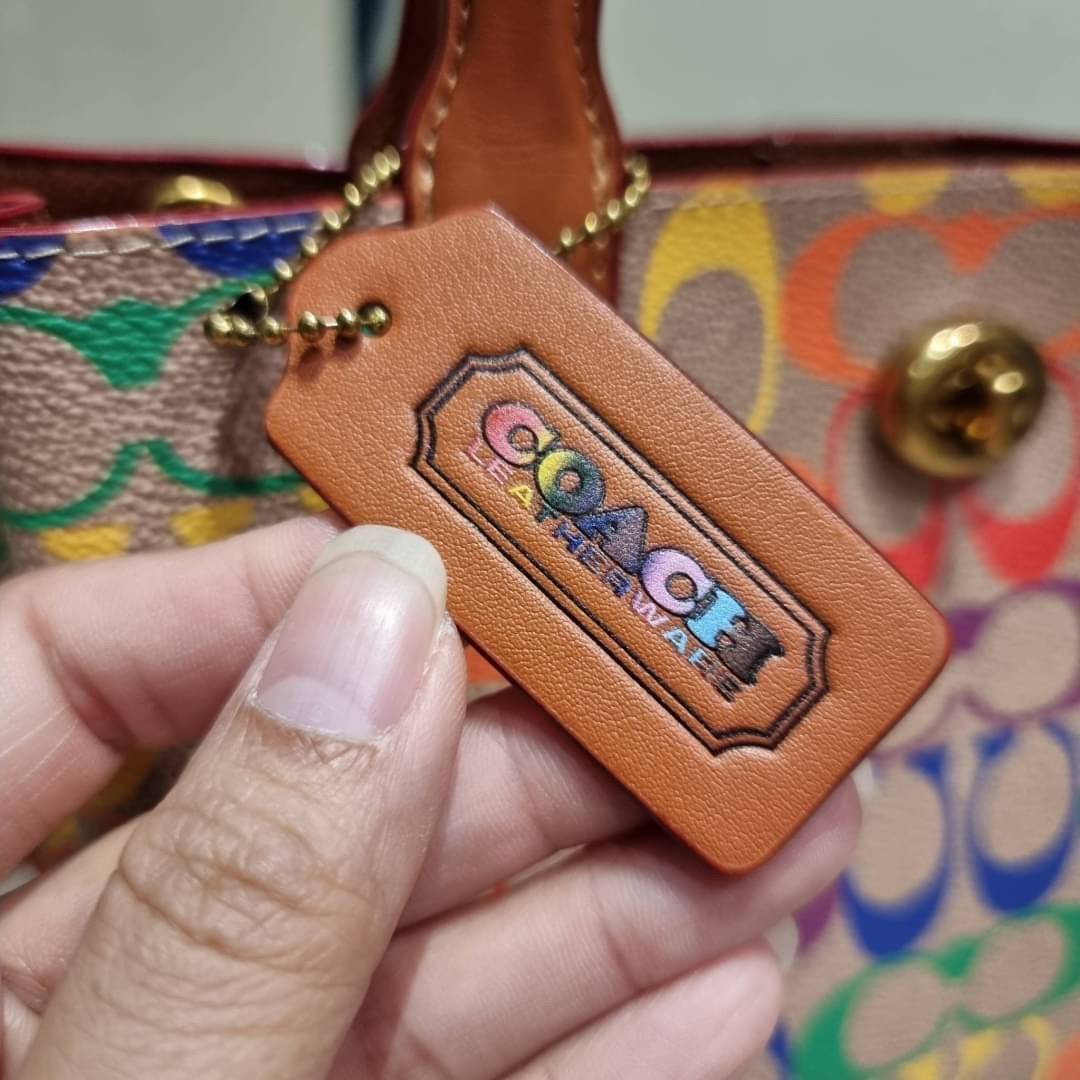 COACH CA102 WILLOW TOTE 24 IN RAINBOW SIGNATURE CANVAS ไปให้สุดกับความเลิศของลวดลายสายรุ้ง ที่แต่งแต้มลงบนกระเป๋าทรงโท้ท ไซส์กำลังสวย พกพาได้สะดวก มีตัวบิดล็อคที่ปากกระเป๋าด้านหนึ่ง และกระดุมแม่เหล็กอีกด้านหนึ่ง ภายในโล่งกว้าง เก็บของได้เป็นสัดส่วนไปเลย ม