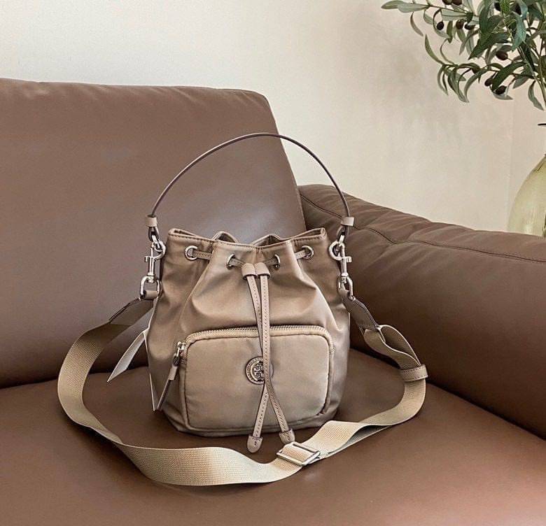 Tory Burch Virginia Nylon Bucket Bag / Tory Burch logo-plaque bucket bag กระเป๋าสะพายทรงบัคเก็ต เปิด-ปิดหนังรูดปากกระเป๋า มีหูหิ้วในตัว คล้องแขนเก๋ๆ ภายในเป็นช่องโล่ง มีช่องย่อย ใส่ของสำคัญจุกจิกได้ มีสายครอส จะสะพายไปไหนก็ได้ทุกโอกาส สวยเลิศทุกสี พร้อมส่