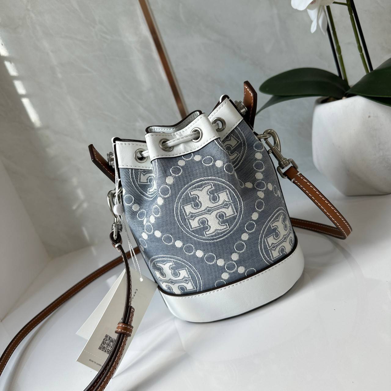TORY BURCH Mini T Monogram Denim Bucket Bag คอลเลคชั่นใหม่ รูปแบบคลาสสิค พกพาความหรูหราไปได้ทุกที่ด้วยกระเป๋าทรง Bucket ขนาดกลางและปิดด้วยเชือกรูดพร้อมโลโก้แวววาว วัสดุผ้าเดนิมแจ็คการ์ด ตัดขอบหนังแท้ สวยหรู ทันสมัยสุดๆคะ