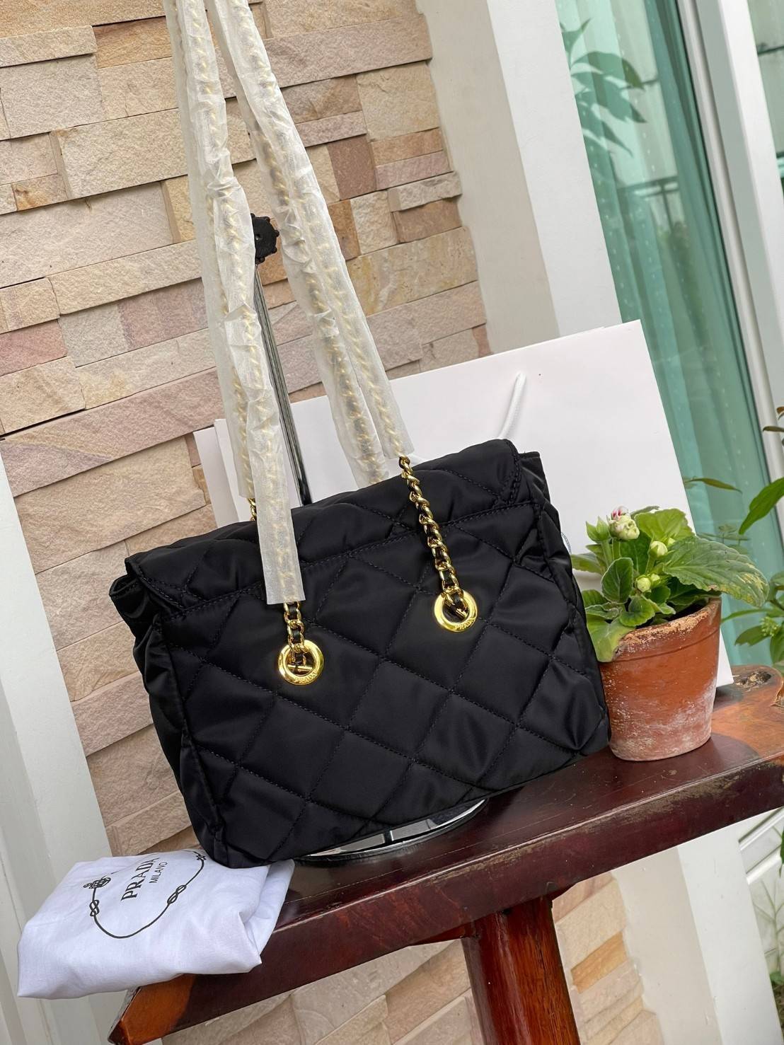 Prada Black Quilted Nylon Vintage Shoulder Bag ถือว่าเป็นแบรนด์ที่ได้รับการขนานนามว่าเป็น "แบรนด์คลาสสิกที่แปลกใหม่ ดูเก่าแต่ทันสมัย" กระเป๋าสะพายไหล่ใบนี้ วัสดุเป็นไนลอนที่ถือเป็น Iconic ของแบรนด์ มาพร้อมกับดีเทลที่ใช้สายสะพายโซ่ร้อยเข้ากับหนัง