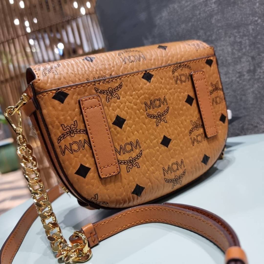 M.C.M MINI PATRICIA CROSSBODY IN VISETOS กระเป๋าสะพายไซส์มินิ แรงดีไม่มีตกน้า คอลเลคชั่นนี้ดีไซน์แปลกใหม่ ทรงโค้งมน สวยหรู ด้านข้างตกแต่งหมุดทองรอบใบ วัสดุตัวกระเป๋าเป็นหนังแคนวาสคุณภาพดี ภายในเป็นหนังกลับสีส้มโดดเด่นเป็นเอกลักษณ์ มีช่องใส่บัตรแยกให้ เปิด