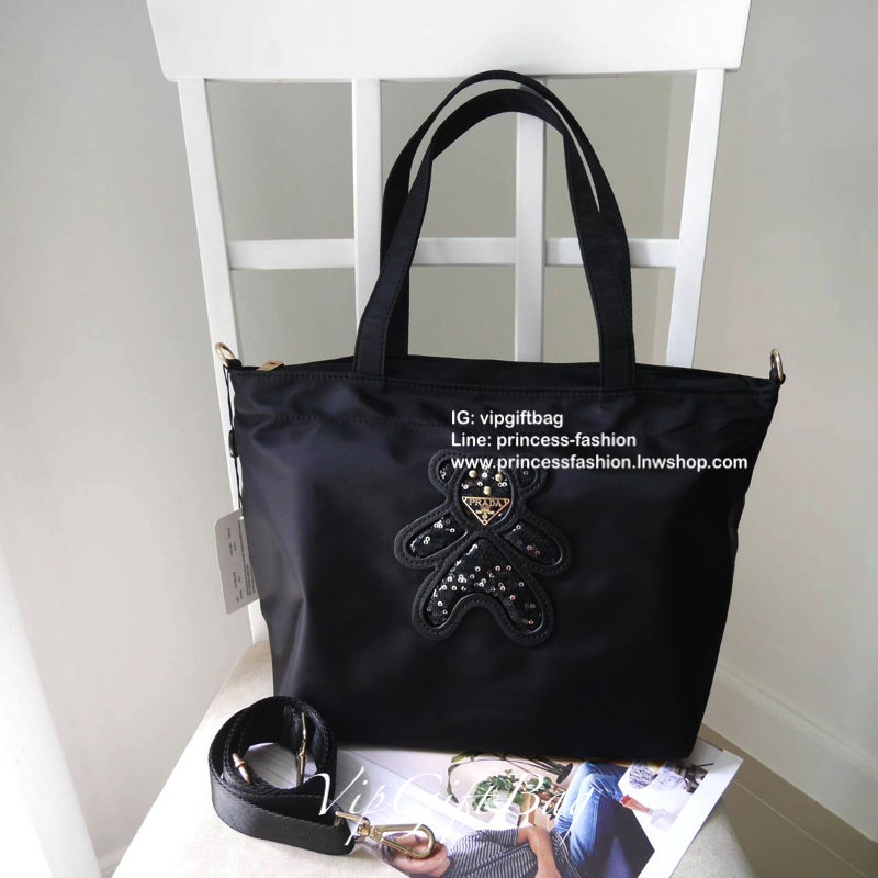 เอาใจคนชอบกระเป๋าไซส์กลาง *มาพร้อมสายยาว สำหรับกระเป๋าอเนกประสงค์ ทรง TOTE จากแบรนด์ PRADA เป็น กระเป๋าผ้าไนล่อน ตามแบบฉบับของแบรนด์เลย ใบนี้มีสายยาวให้ค่ะ เลิศมาก สะพายเป็น shoulder bag หรือ ถือได้คะ ด้านหน้าเป็นลายหมี ปั๊กกลิ้ตเตอร์ + logo brand ใช้แล้ว