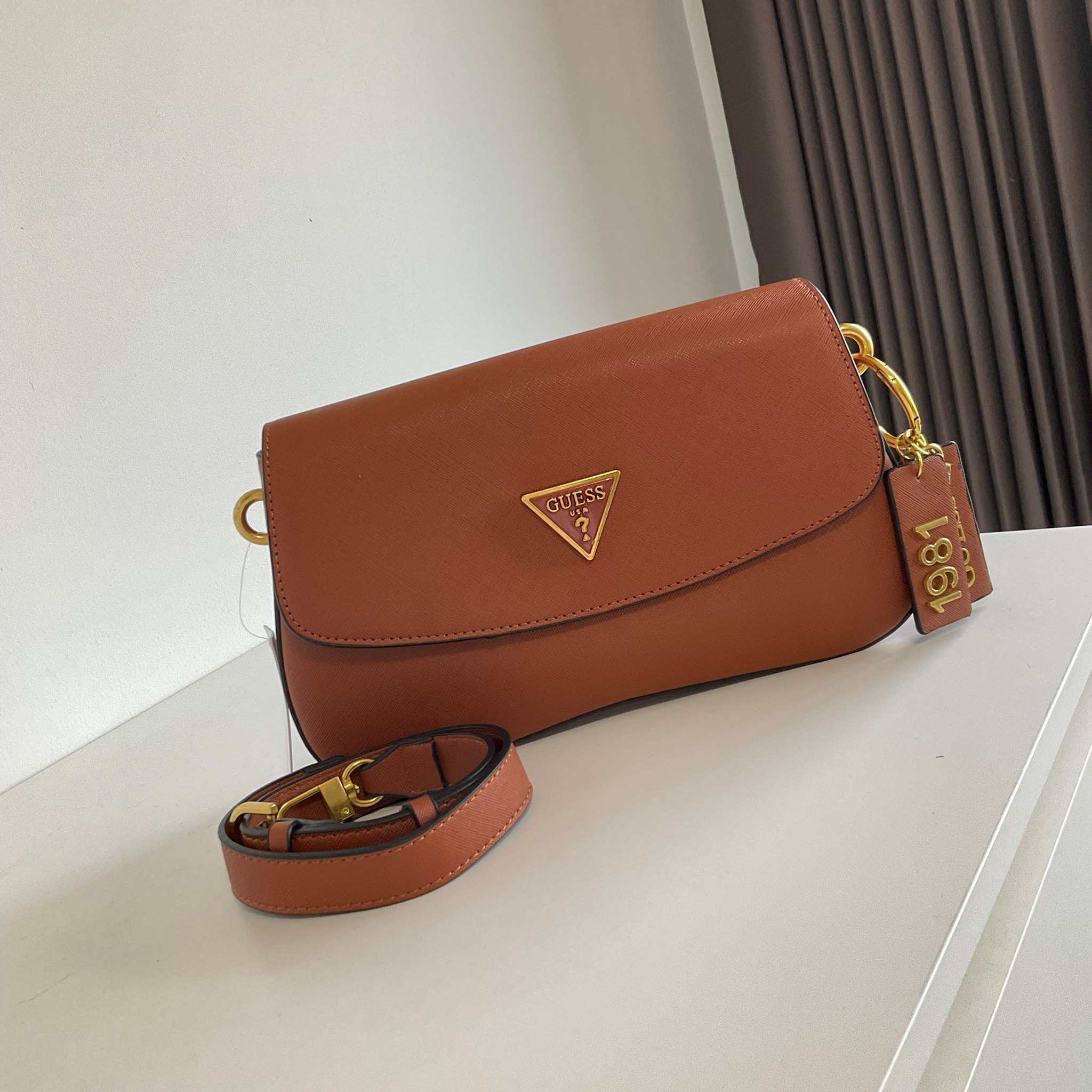 GUESS COLDELIA LOGO FLAP BAG กระเป๋าสะพายไหล่ หนังสวยหรู พิมพ์ลาย อะไหล่ทอง เปิดปิดด้วยกระดุมแม่เหล็ก มีช่องเล็กด้านหน้าหนึ่งช่อง ด้านในใส่กระเป๋าสตางค์ยาว มือถือได้ทุกรุ่น พร้อมช่องซิปแยกให้ มาพร้อมสายสะพายไหล่ปรับและถอดได้ ไอเท็มล่าสุดใบนี้ต้องมีนะคะ