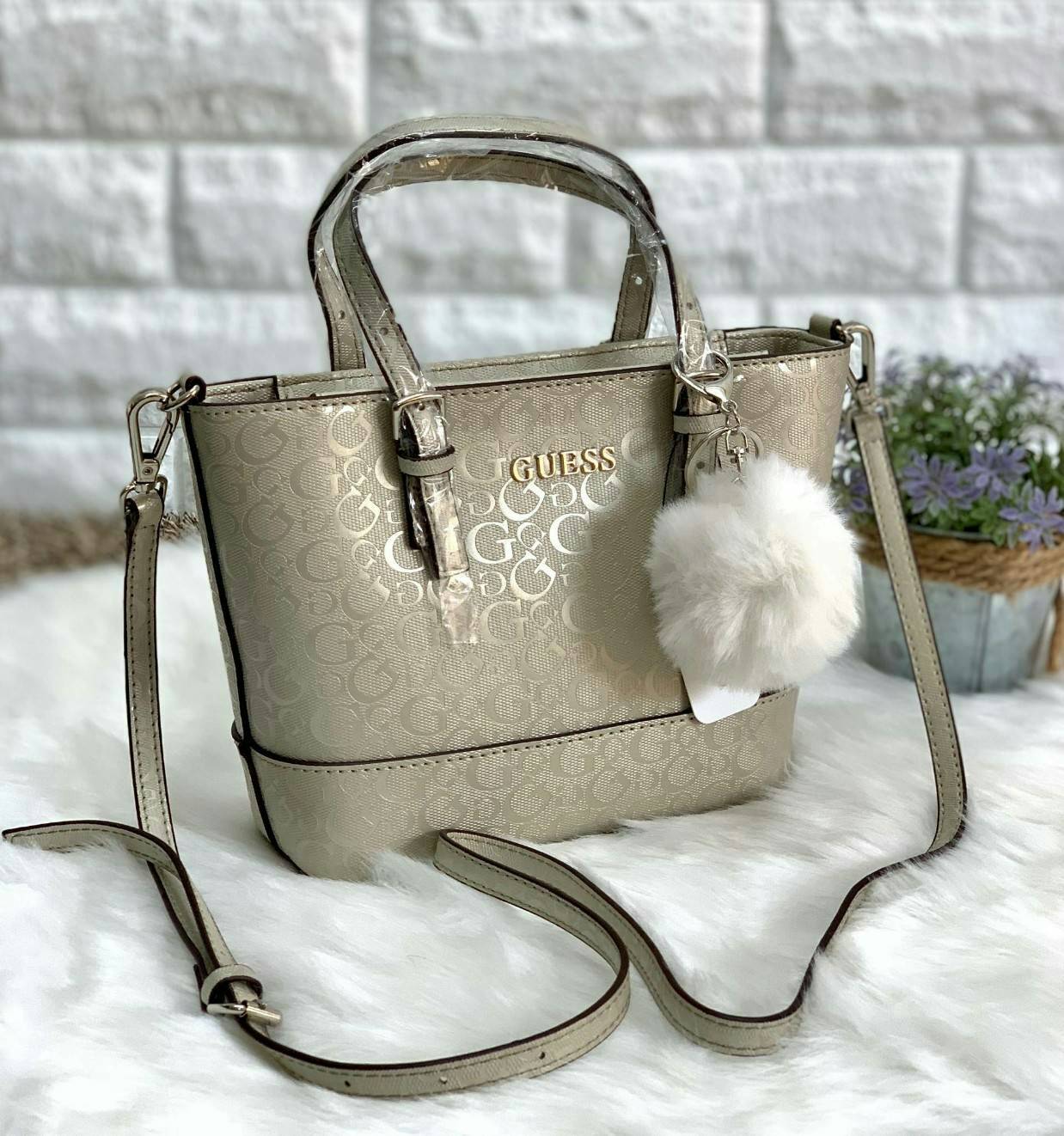 GUESS MINI TOTE BAG กระเป๋าถือหรือสะพายข้าง วัสดุหนังปั้มแบรนด์ทั้งใบ ด้านหน้ามีโลโก้แบรนด์ พร้อมห้อยพวงปอมปอมขนนิ่มมาให้ด้วยค่ะ เปิดปิดกระเป๋าแบบซิป ภายในใส่กระเป๋าสตางค์ใบยาวได้ค่ะ มีช่องซิปและช่องเล็กใส่ของจุกจิกนะค่ะ มาพร้อมสายยาวถอดออกได้เลื่อนปรับระ