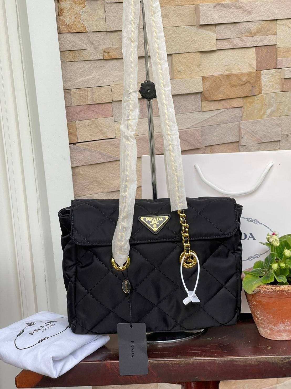 Prada Black Quilted Nylon Vintage Shoulder Bag ถือว่าเป็นแบรนด์ที่ได้รับการขนานนามว่าเป็น "แบรนด์คลาสสิกที่แปลกใหม่ ดูเก่าแต่ทันสมัย" กระเป๋าสะพายไหล่ใบนี้ วัสดุเป็นไนลอนที่ถือเป็น Iconic ของแบรนด์ มาพร้อมกับดีเทลที่ใช้สายสะพายโซ่ร้อยเข้ากับหนัง