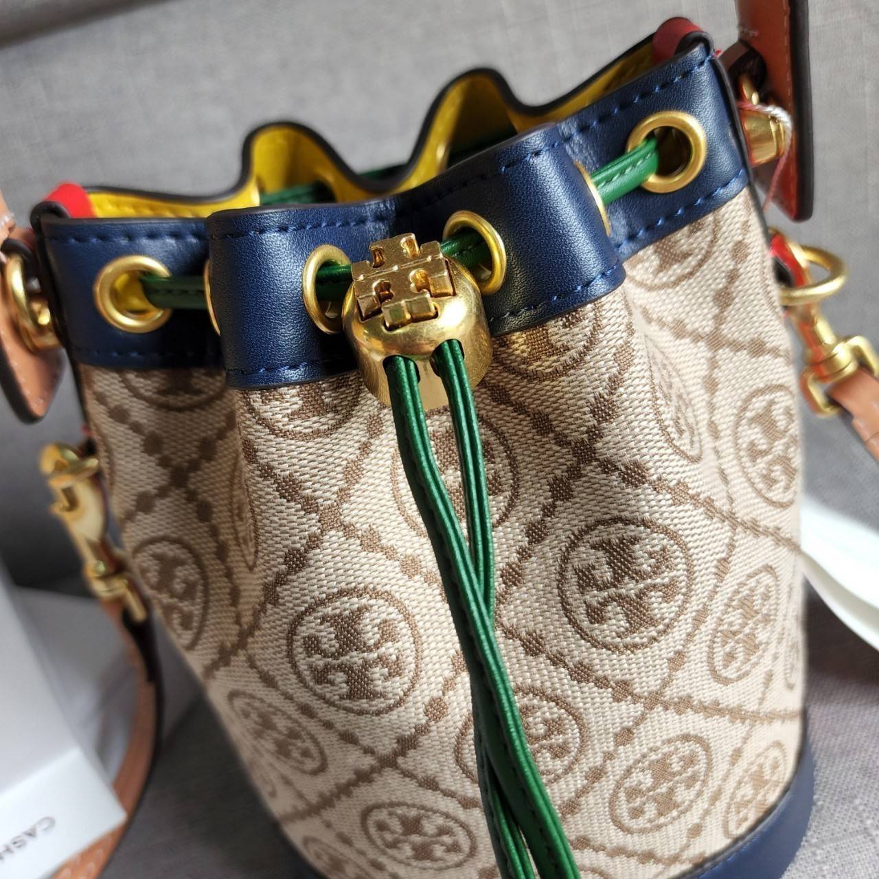 TORY BURCH T MONOGRAM COLORBlOCK JACQUARD MINI BUCKET BAG คอลเลคชั่นใหม่ล่าสุด ครอบครองก่อนใคร รุ่นบัคเก็ตทรงจีบ วัสดุ jacquard สลับหนังแท้ ตัดขอบข้างสีแดงทำให้ดูโดดเด่น หูจับหนังแท้ เปิด ปิด แบบหูรูด ภายในช่องโล่งกว้าง มาพร้อมสายสะพายข้างหนังแท้ ปรับระดั
