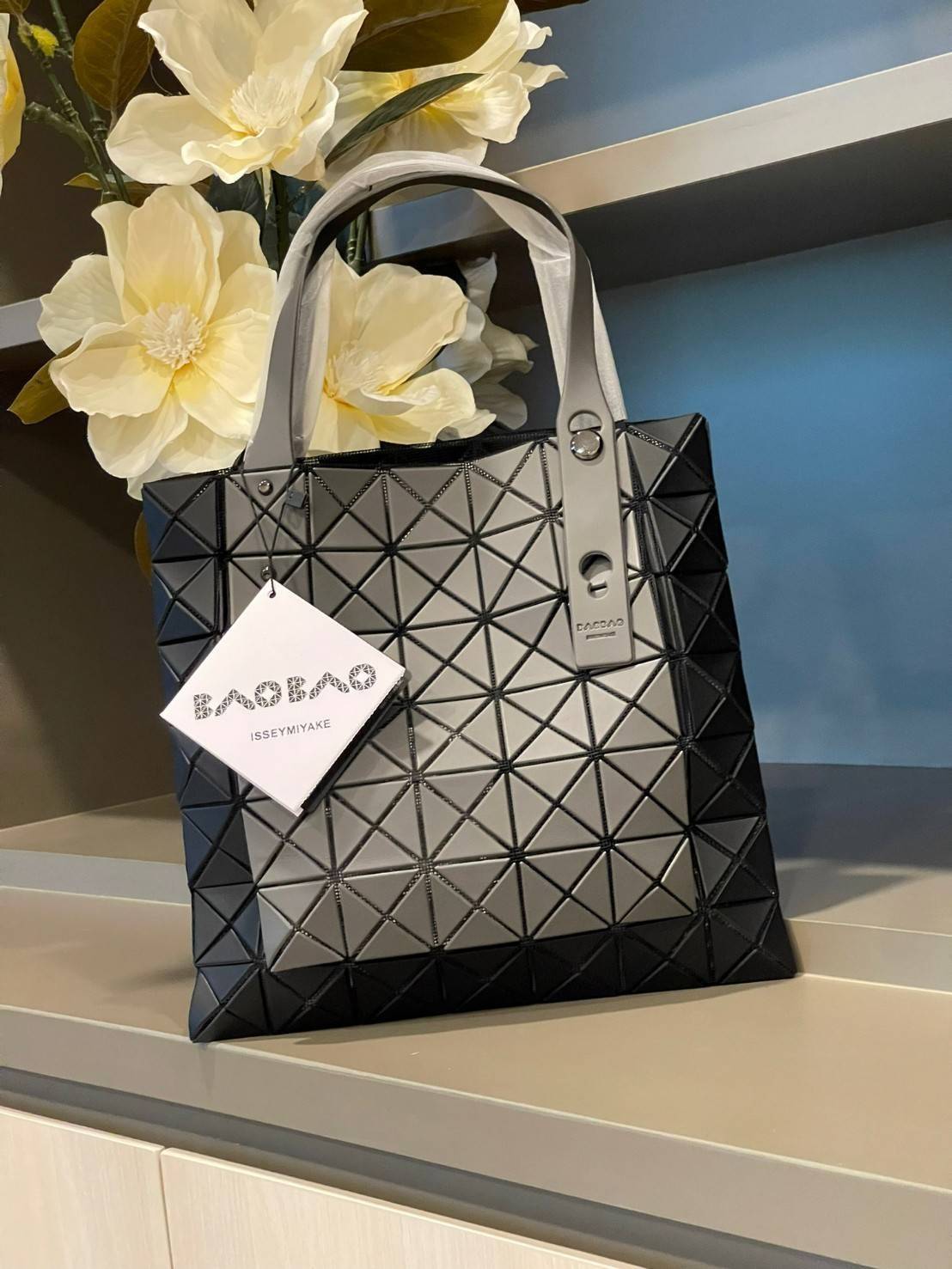 Baobao Issey Miyake Prism Kangaroo tote bag กระเป๋าถือทรงโท้ทที่ประดิษฐ์ขึ้นอย่างเชี่ยวชาญในญี่ปุ่น มาพร้อมแผงเรขาคณิตสำหรับการออกแบบที่ได้รับแรงบันดาลใจจากกระดาษพับ ซิลลูเอทอันเป็นเอกลักษณ์นี้ปิดท้ายด้วยสายรัดแบบอสมมาตร มีการพัฒนาโครงสร้างทรงสามเหลี่ยมเพ