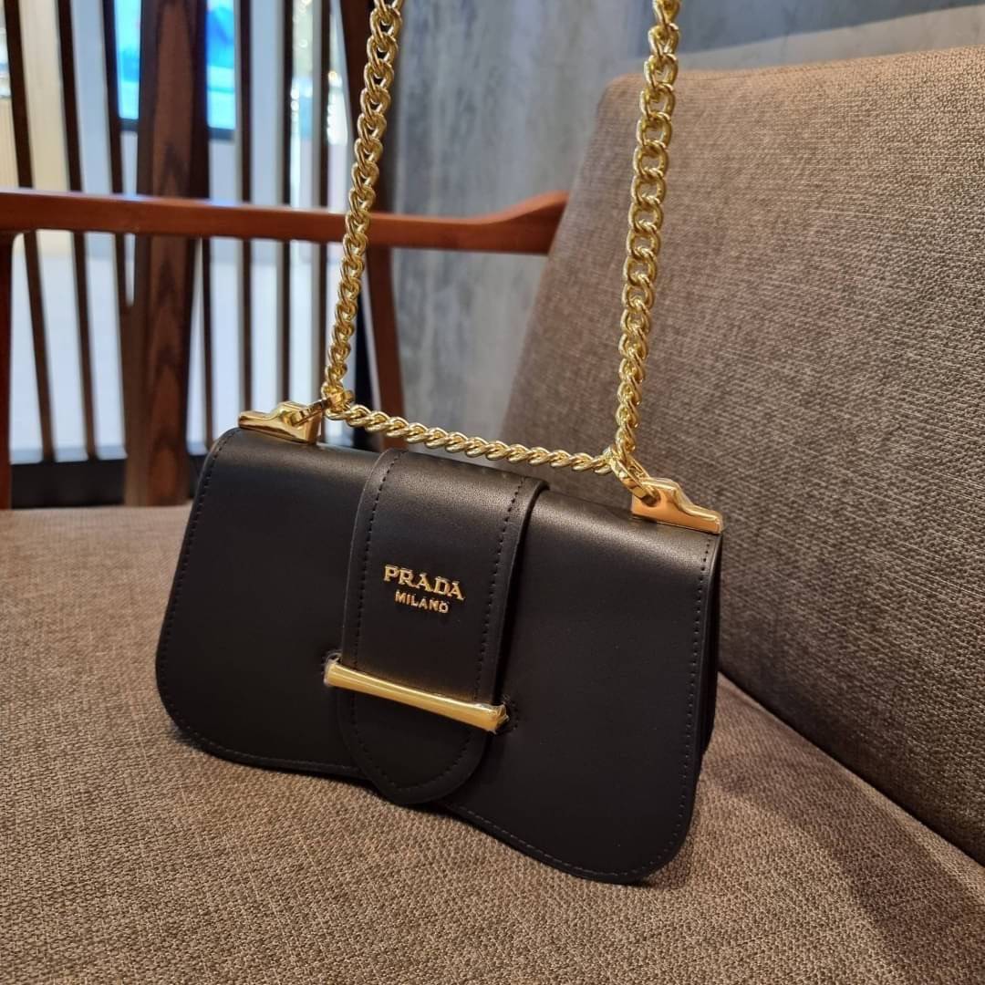 PRADA FRAGRANCE SHOULDER BAG WITH GWP ไอเท็มสุดโปรดที่ควรค่าแก่การครอบครองและเก็บสะสม กระเป๋าสะพายไหล่ สวยคม สีดำคลาสสิคตัดกับอะไหล่ทองเป็นอย่างดี วัสดุหนังแท้เต็มใบ เปิดปิดด้วยแถบหนังสอดในช่อง ใช้งานสะดวก พกพาง่าย ขนาดกำลังสวย สายสะพายในตัว สะพายได้หลากห
