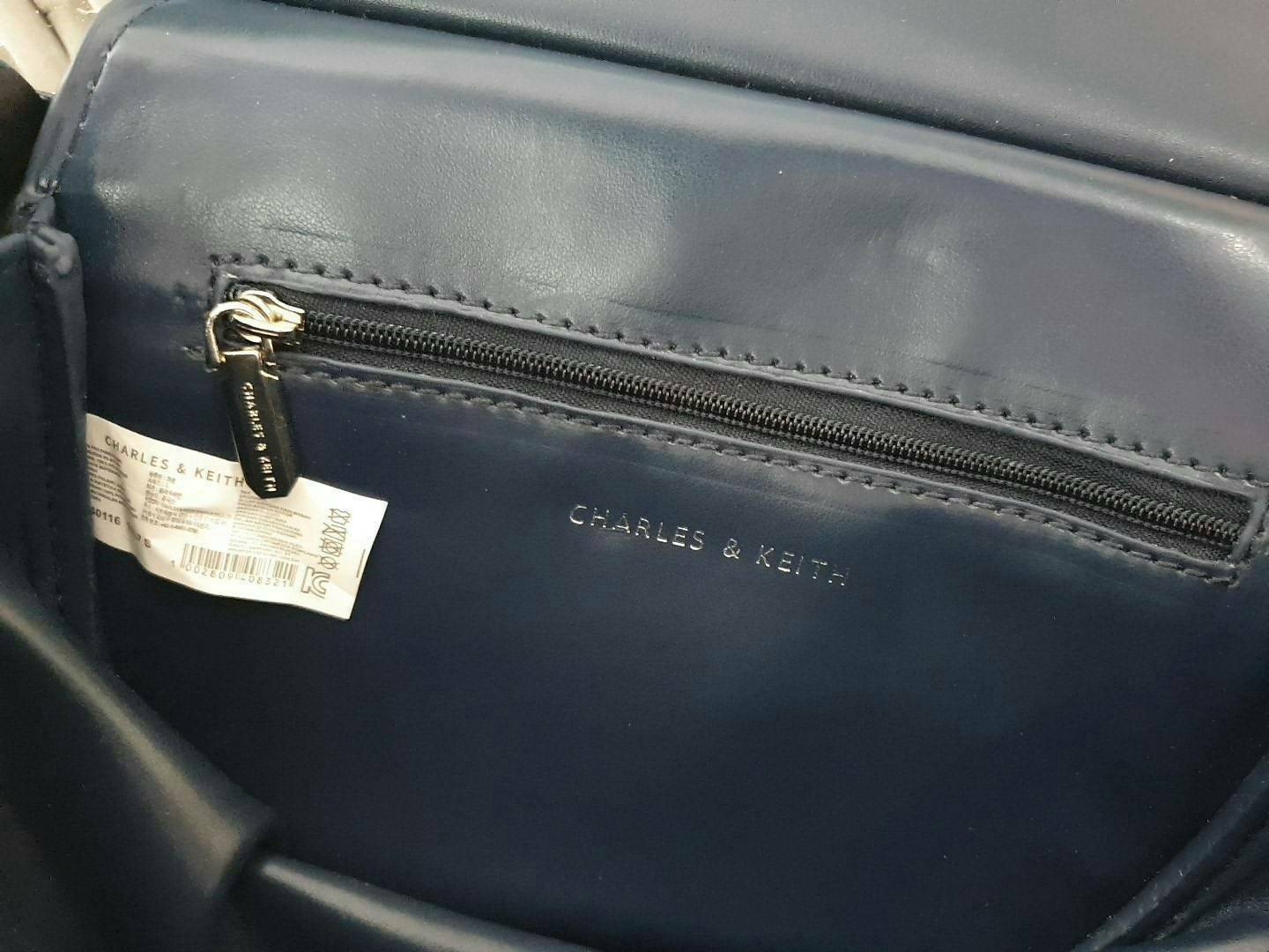 CHARLES & KEITH รุ่น LEATHER SATIN SCARF CROSSBODY BAG SL2-50150828 ราคาปกติช้อป ( ฿3,590.00 ) กระเป๋าถือ และ สะพาย ทรงโค้งมน หนังเรียบ ตั้งอยู่ทรง ด้านหน้าติดโลโก้แบรนด์ อะไหล่เงิน หูจับสายกระเป๋าร้อยเข้ากับห่วงเหล็กกลมๆ ด้วยผ้าลายสวยงามผูกเป็นโบว์เก๋ๆ ถ