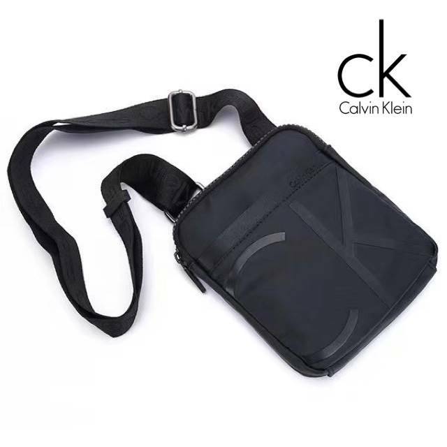 Cavin Klein Crossbody Bag กระเป๋าสะพายข้าง วัสดุหนังโพลีเอสเตอร์ น้ำหนักเบา สายสะพายปั้กโลโก้ ปรับความยาวได้ฟรีไซส์ ด้านหน้ามี1ช่องซิปใส่ของได้ หัวซิปปั้มโลโก้ทุกจุด เปิดปิดด้วยซิปเดียวด้านบน ด้านหน้ามีโลโก้เป็นอักษรย่อสวยงาม ขนาดกระเป๋าใส่มินิไอแพคกระเป๋