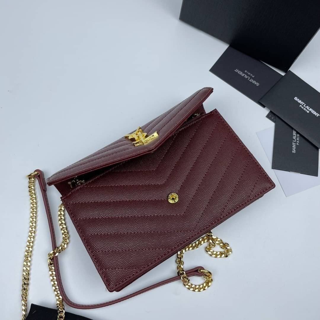 หนังแท้ YSL Yves Saint Laurent Envelope WOC 7.5” รุ่นฮอตปรอทแตก ทรงฐานตั้งได้ เป็นการดีไซน์กึ่งกระเป๋าสตางค์ ที่มาพร้อมสายสะพายยาว (เป็นสายโซ่ที่ต่อกับหนัง) สายถอดได้ (ปรับระดับไม่ได้) ถือเป็นคลัชก็สวยมากเลยค่ะ เป็นอีกหนึ่งรุ่นที่ให้ความรู้สึกเรียบแต่โก้ห