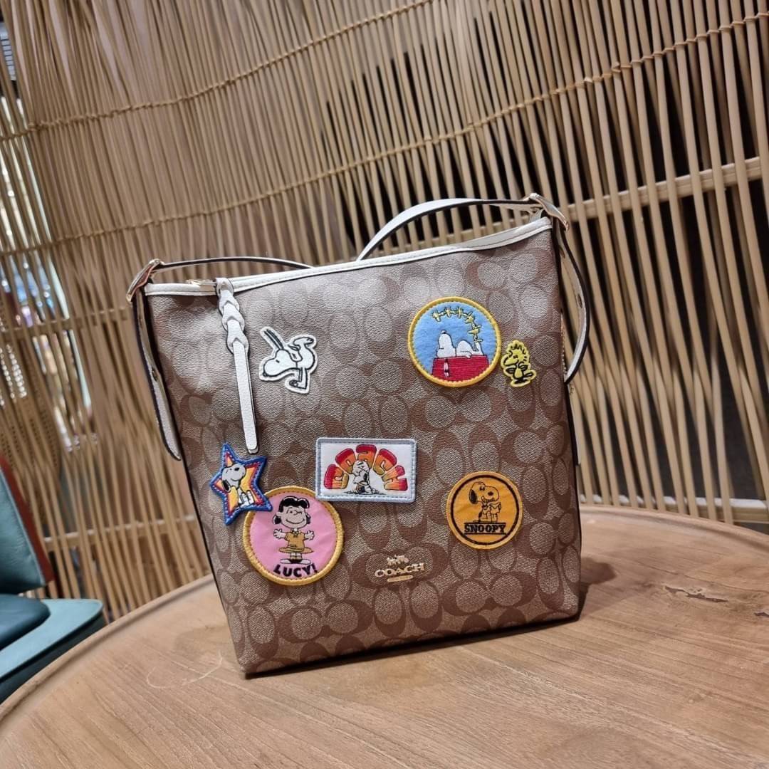 OUTLET 】COACH C4112 COACHxPEANUTS VAL DUFFLE IN SIGNATURE CANVAS WITH VARSITY PATCHES ใหม่ล่าสุด กระเป๋าทรงดัฟเฟิล ที่มาพร้อมเหล่าผองเพื่อนสนูปพี สวยมีเอกลักษณ์ ทรงกระเป๋าไม่ซ้ำใคร แถมยังใส่ของได้จุใจไปอีก วัสดุหนังแคนวาสคุณภาพดี ด้านหลังมีช่องซิป กระเป๋า