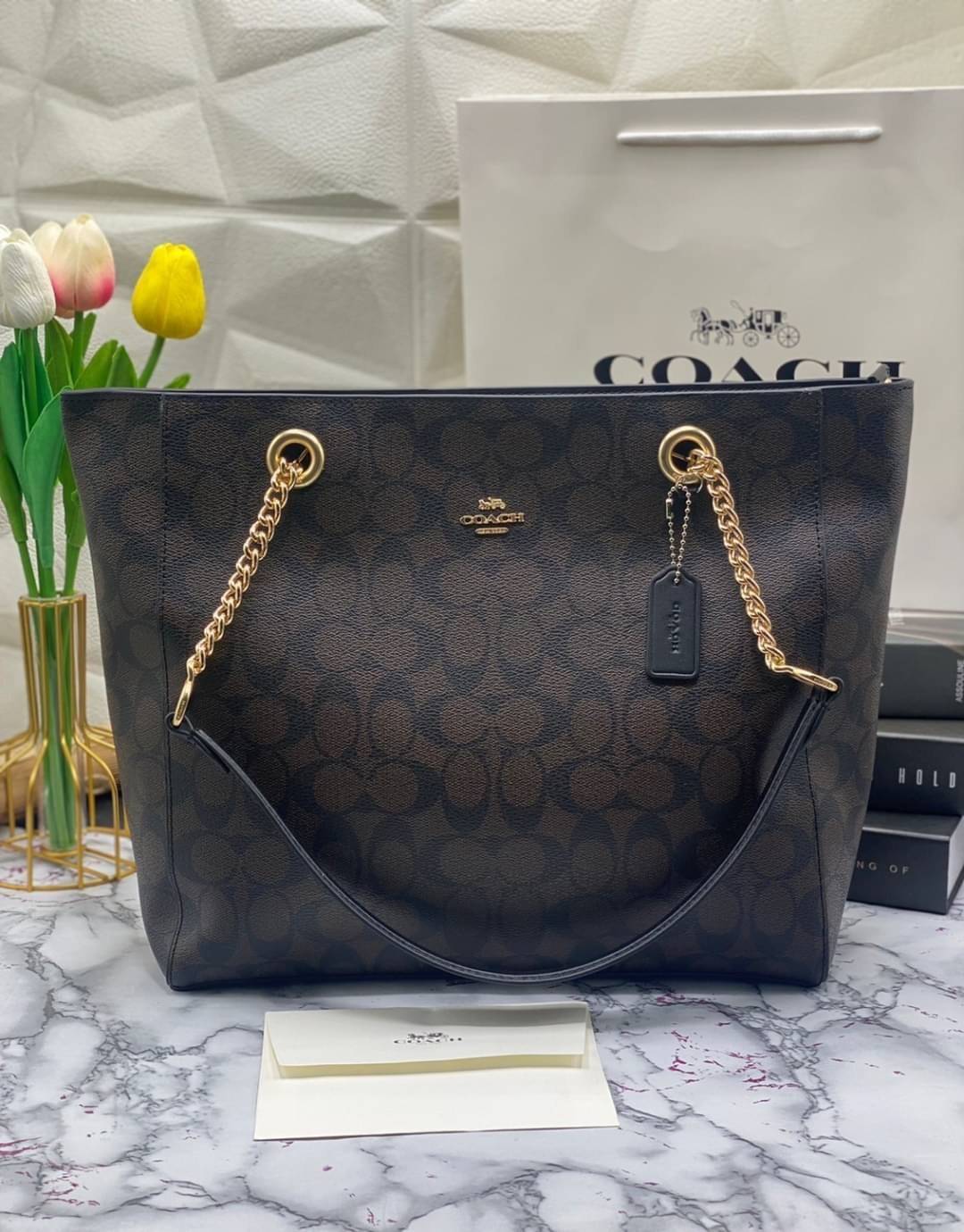 COACH Tote in Signature Canvas Bag กระเป๋าสะพายทรงช้อปปิ้ง สายกระเป๋าเป็นหนังสลับโซ่ทองสวยงาม เพิ่มความหรูหรา ภายในโล่งกว้างใส่ของได้เยอะมาก วัสดุ Canvas เคลือบลายซิกเนเจอร์และหนัง พร้อมซิปกลางเก็บของได้มิดชิดเลยค่ะ มี 3 สี น้ำตาล ดำ ขาว