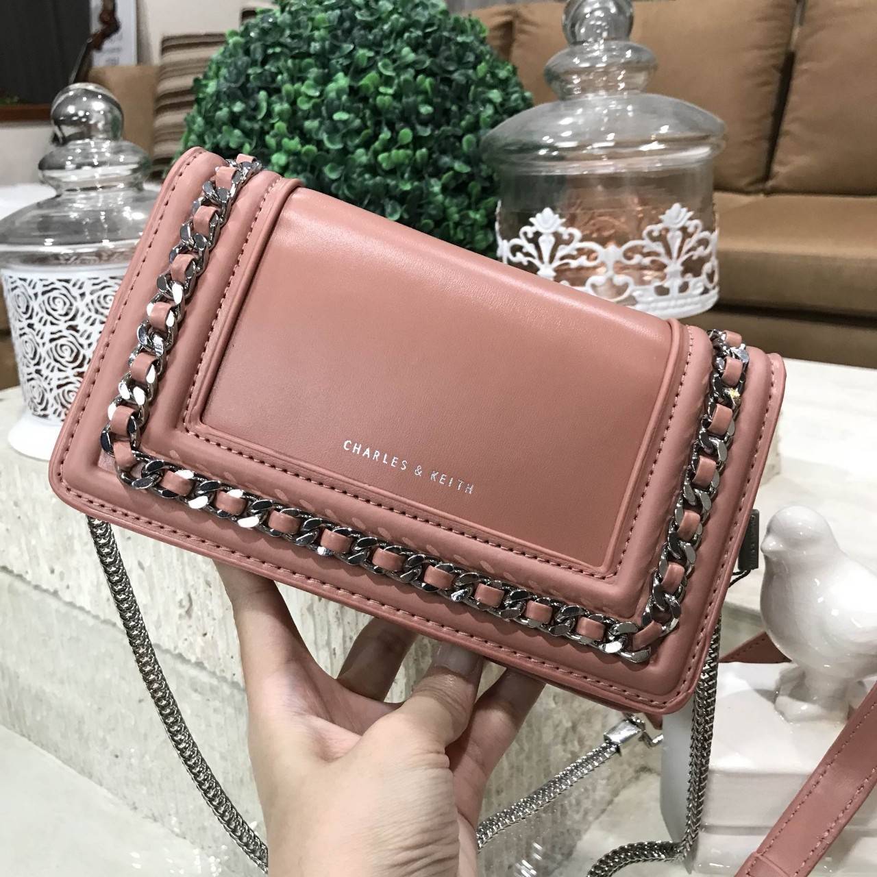 NEW ARRIVAL! CHARLES & KEITH CHAIN DETAIL CROSSBODY BAG กระเป๋าสะพายทรงสี่เหลี่ยมรุ่นชนช็อปขนาดกำลังดีวัสดุหนังนิ่มเรียบประดับด้วยโซ่ด้านหน้าดูมีดีเทล เปิดปิดด้วยกระดุมแม่เหล็ก ภายในมีช่องใส่บัตรและช่องซิป มาพร้อมสายโซ่ต่อหนังถอดถือเป็นคลัชได้ ภาพถ่ายสินค