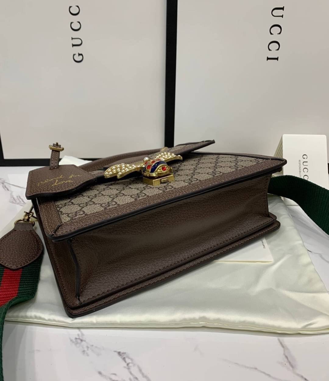 พรีเมี่ยมกิ๊ฟแท้ 100% 】Gucci Queen Margaret GG small top handle bag 476541 Dark Coffee งานหนังแท้ กระเป๋าที่ใช้เป็น Everyday Bag สามารถใช้งานได้บ่อยครั้งและสามารถสะพายไปทำกิจกรรมต่าง ๆ ได้ทุกวันตัวกระเป๋าอยู่ทรงสวย จุดเด่นมีผีเสื้อแสนสวย อีกหนึ่งไอเท็มที่