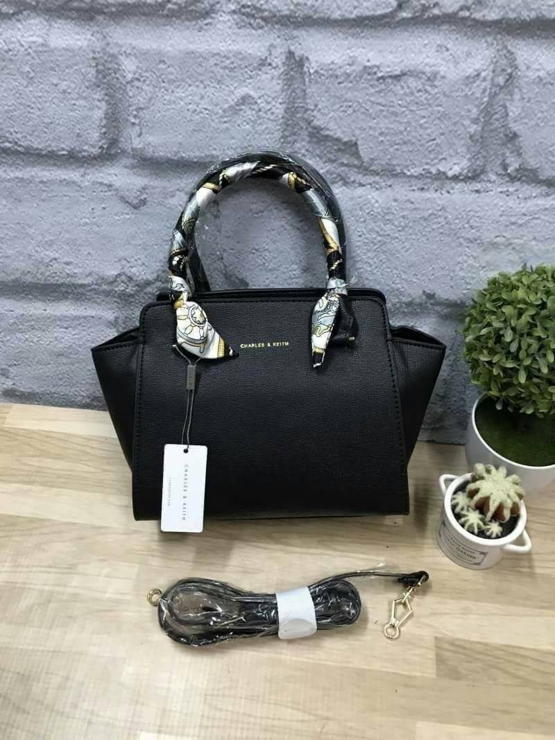 CHARLES&KEITH MINI TRAPEZ BAG พร้อมส่งรุ่นฮิตในตำนานรุ่นขายดี !! !กระเป๋าถือหรือสะพายหนังsaffiano พร้อมสายสะพายยาว115cmปรับความยาวได้5ระดับ ด้านล่างมีหมุดรองฐาน ทั้ง4มุม หูจับสูง14cmมีผ้าพันรอบสามารถถอดออกได้ ลายและสีสวยงามเข้ากับกระเป๋า ขนาดกำลังดีและน้ำ