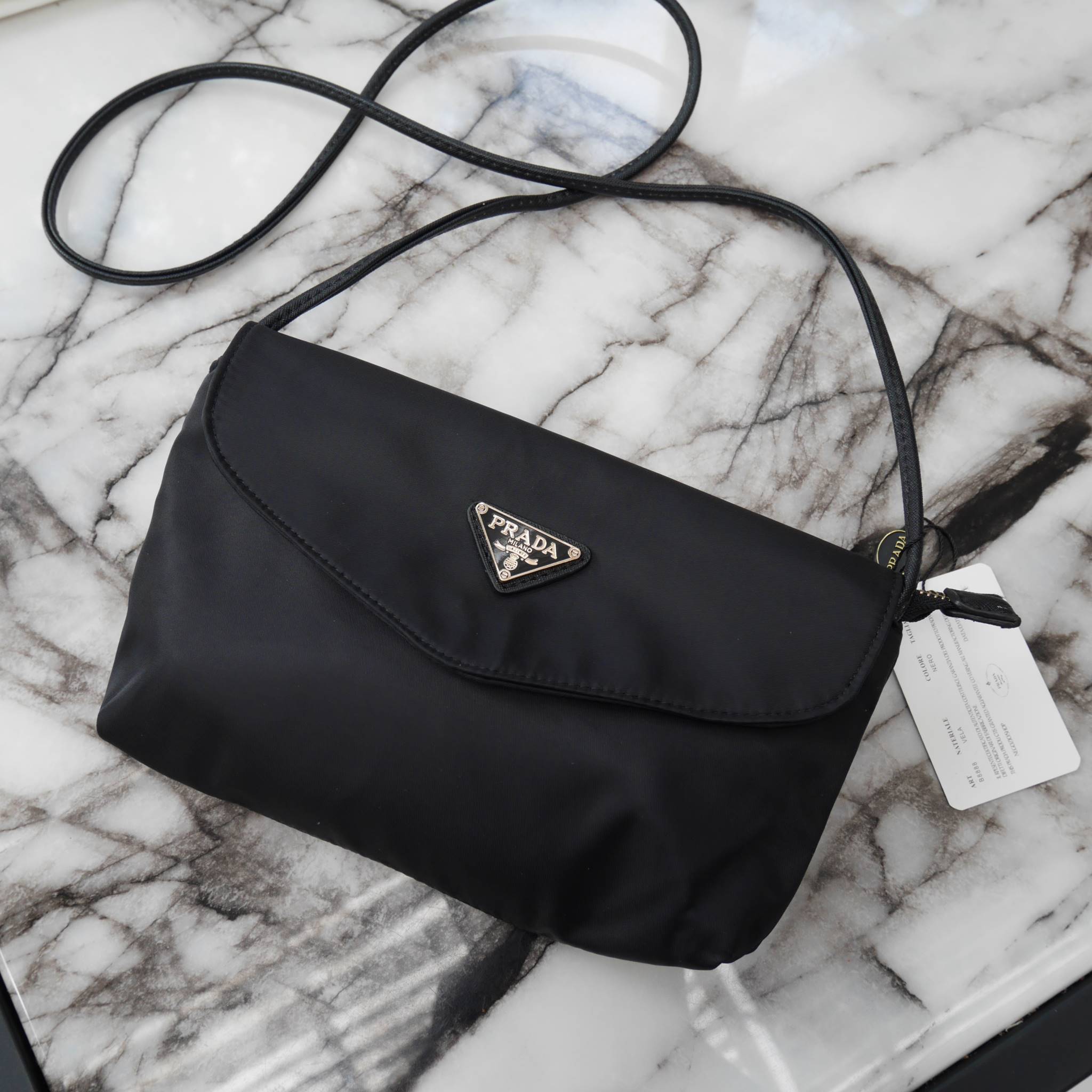 Best Seller! จากงานพรีเมี่ยมกิ้ฟ จากเคาเตอร์ต่างประเทศ จากแบรนด์ PRADA ค่า เป็น กระเป๋าผ้าไนล่อน ตามแบบฉบับของแบรนด์เลย ใบนี้มีสายยาวให้คะ เลิศมาก สะพายเป็น shoulder bag ได้เลย ขนาดกำลังดีคะ ตัวกระเป๋าเบามาก ใส่มือถือได้ทุกรุ่น ใช้แล้วสวยมากๆ อะไหล่ทองหรู