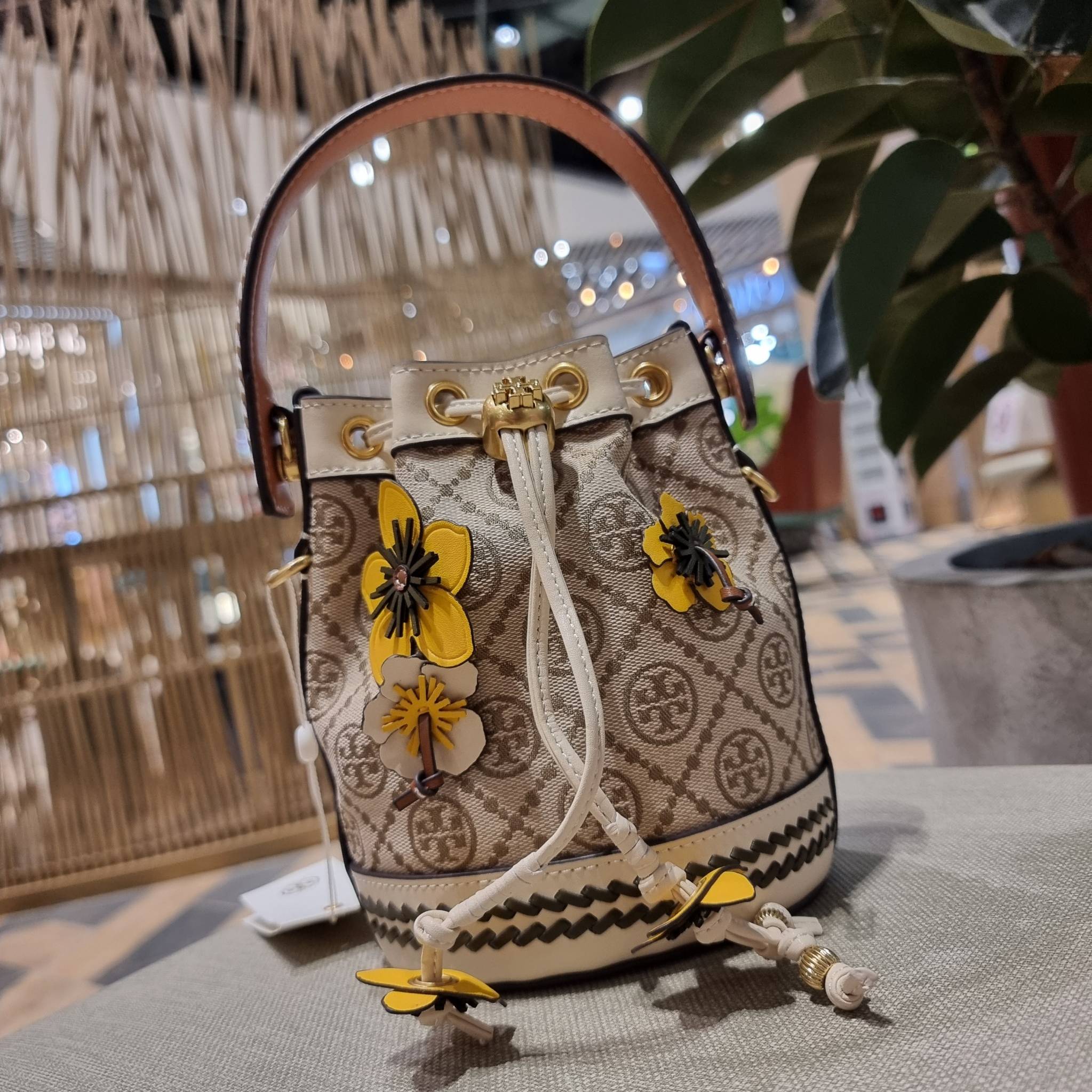 TORY BURCH MINI T MONOGRAM FLORAL BUCKET BAG คอลเลคชั่นใหม่ พร้อมเสิร์ฟความสวยให้ถึงบ้าน!! กระเป๋าบัคเก็ตทรงยอดนิยม ไซส์มินิ ดีไซน์ใหม่ล่าสุด สไตล์งานคราฟ มีลูกเล่นประดับดอกไม้กับตัวกระเป๋า และตัวรูดสาย วัสดุผ้า jacquard ตัดสลับหนังแท้ หูจับและขอบกระเป๋าต