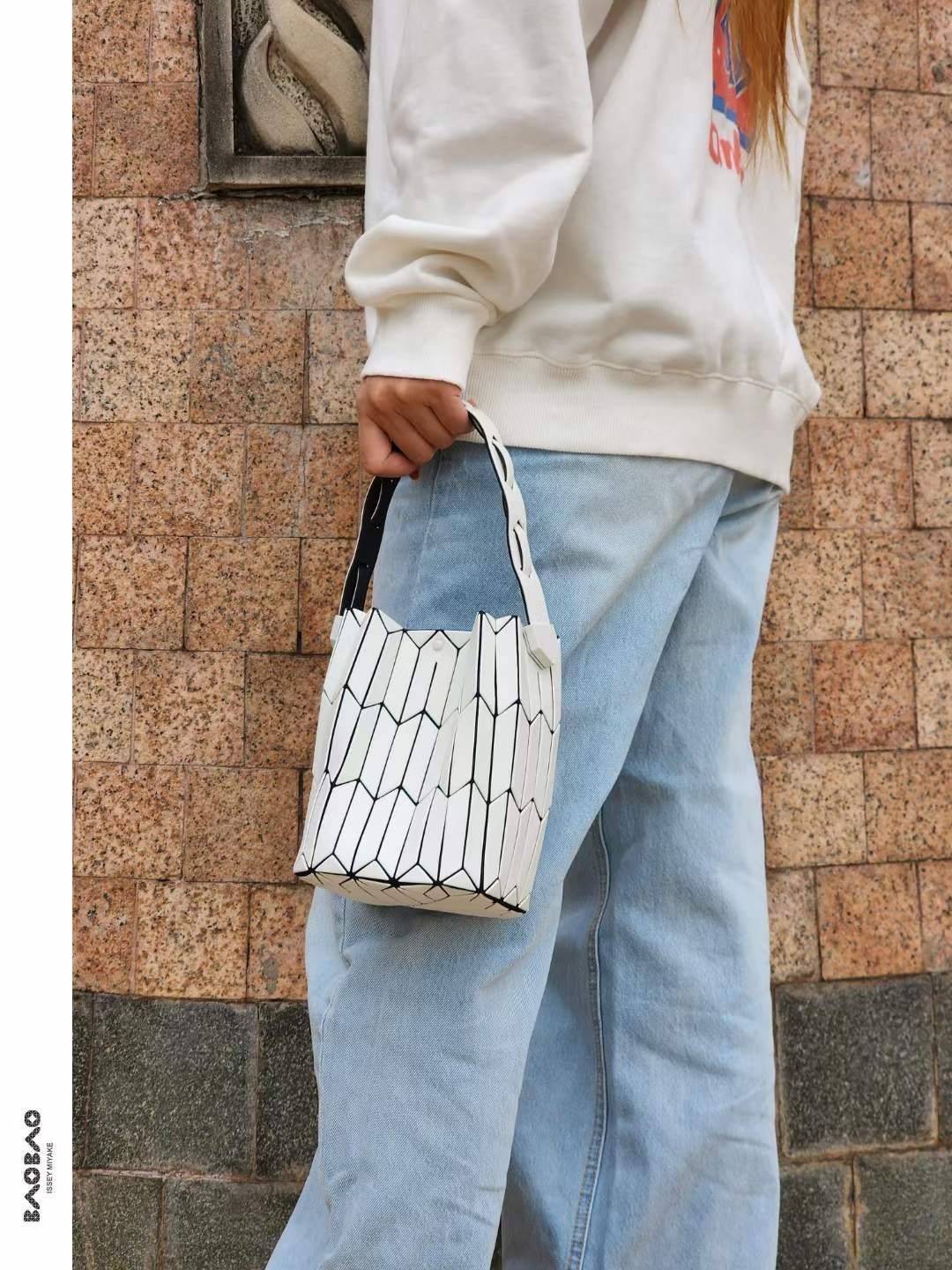 Small : BAO BAO ISSEY MIYAKE SMALL BUCKET เป็นกระเป๋าบัคเก็ตขนาดเล็กสามารถใช้ใส่กระเป๋าสตางค์และโทรศัพท์มือถือได้ ซีรีย์ใหม่นี้มีจุดเด่นที่แผ่นรูปทรงสี่เหลี่ยมด้านขนานในแนวตั้ง เกิดเป็นรูปทรงสามมิติซึ่งแตกต่างไปจากรูปทรงที่เกิดขึ้นจากแผ่นสามเหลี่ยม หูหิ้ว