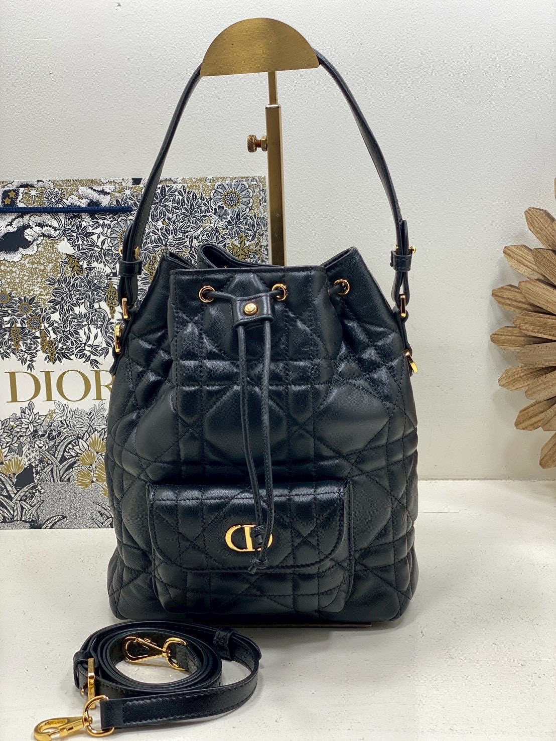 ORI หนังแท้ | Small Dior Caro bucket bag กระเป๋าทรงบักเก็ต รุ่นใหม่ประจำ Fall 2025 โดดเด่นด้วยดีไซน์ที่ทันสมัยและสง่างาม ได้รับการรังสรรค์ขึ้นจากหนังแกะสีดำเดินด้ายลาย Macrocannage พร้อมกับช่องเก็บของขนาดใหญ่แบบเชือกรูดปิด