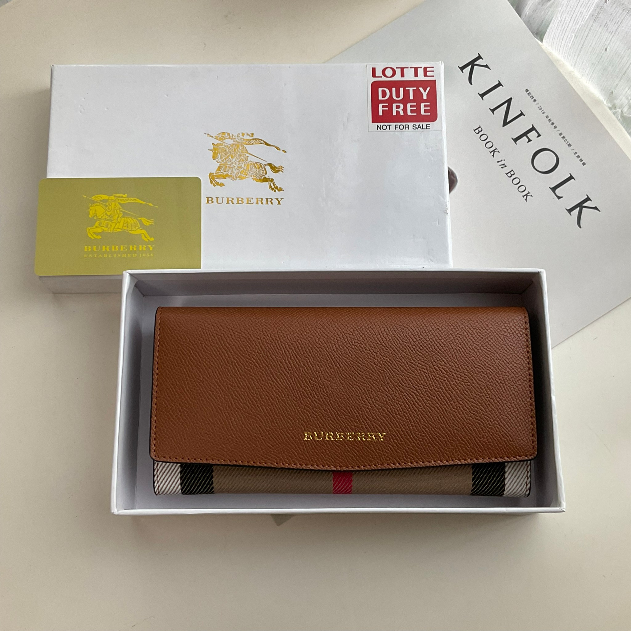 กระเป๋าสตางค์รับทรัพย์ ทรงหรู จากงาพรีเมี่ยมกิ๊ฟ Limited Edition จาก BURBERRY กระเป๋าสตางค์ใบยาวแบบพับกระดุม ทูโทนด้วยหนังแท้คาดผ้าลาย vintage ด้านในมีช่องใส่ธนบัตรยาวทั้งสองฝั่ง ช่องใส่บัตรได้อย่างน้อย 12 ช่อง และช่องเปิดด้วยซิปปั้มแบรนด์อะไหล่ทองสุดหรู 