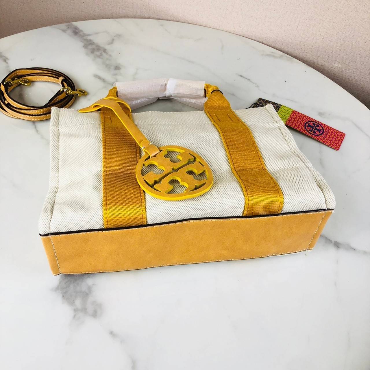 กระเป๋าถือ หรือสะพาย TORY BURCH เปิด - ปิดกระเป๋าด้วยกระดุม ด้านในมีช่องซิป 1 ช่อง และช่องใส่ของ 1 ช่อง มาพร้อมสายสะพาย สามารถถอดและปรับได้ 3 ระดับ